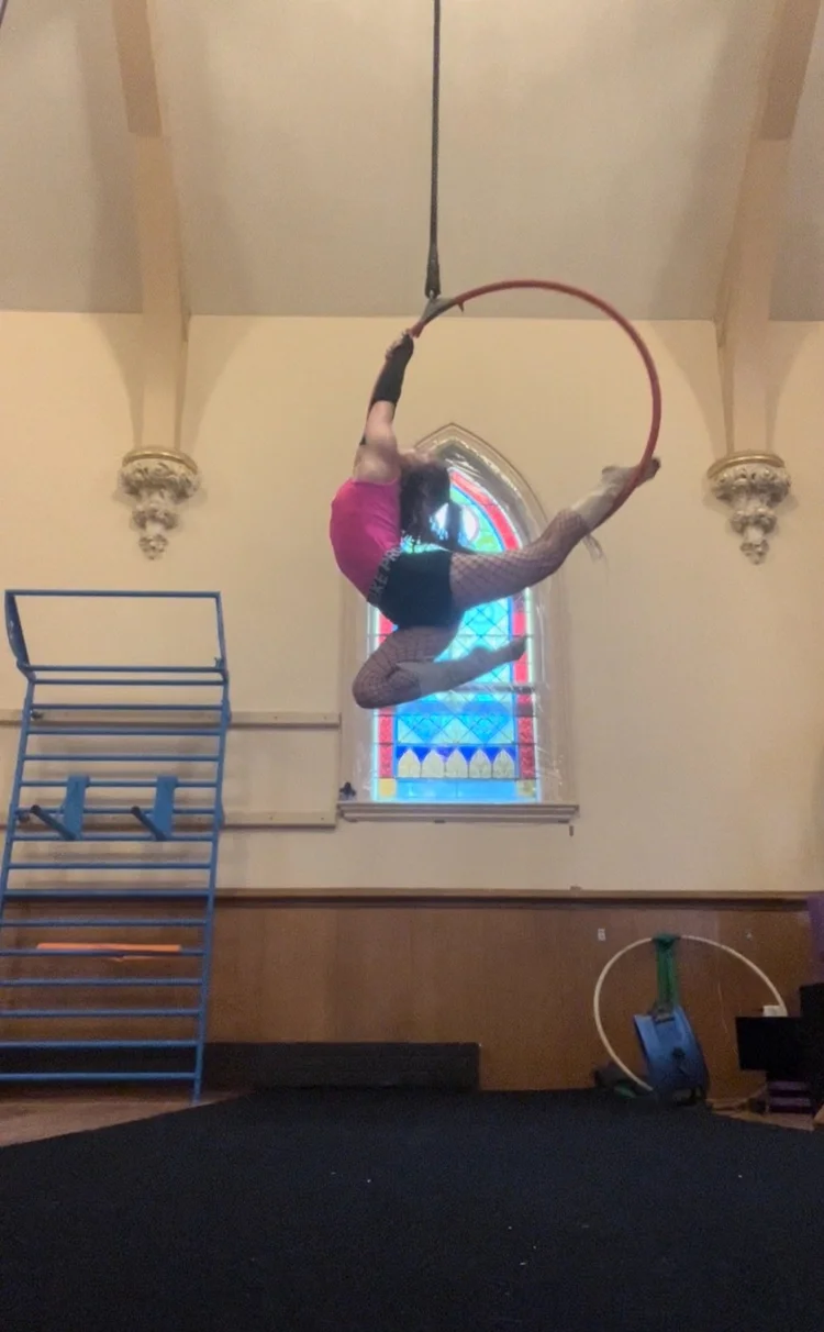 Talia Hazard curled into an aerial hoop in a practice space