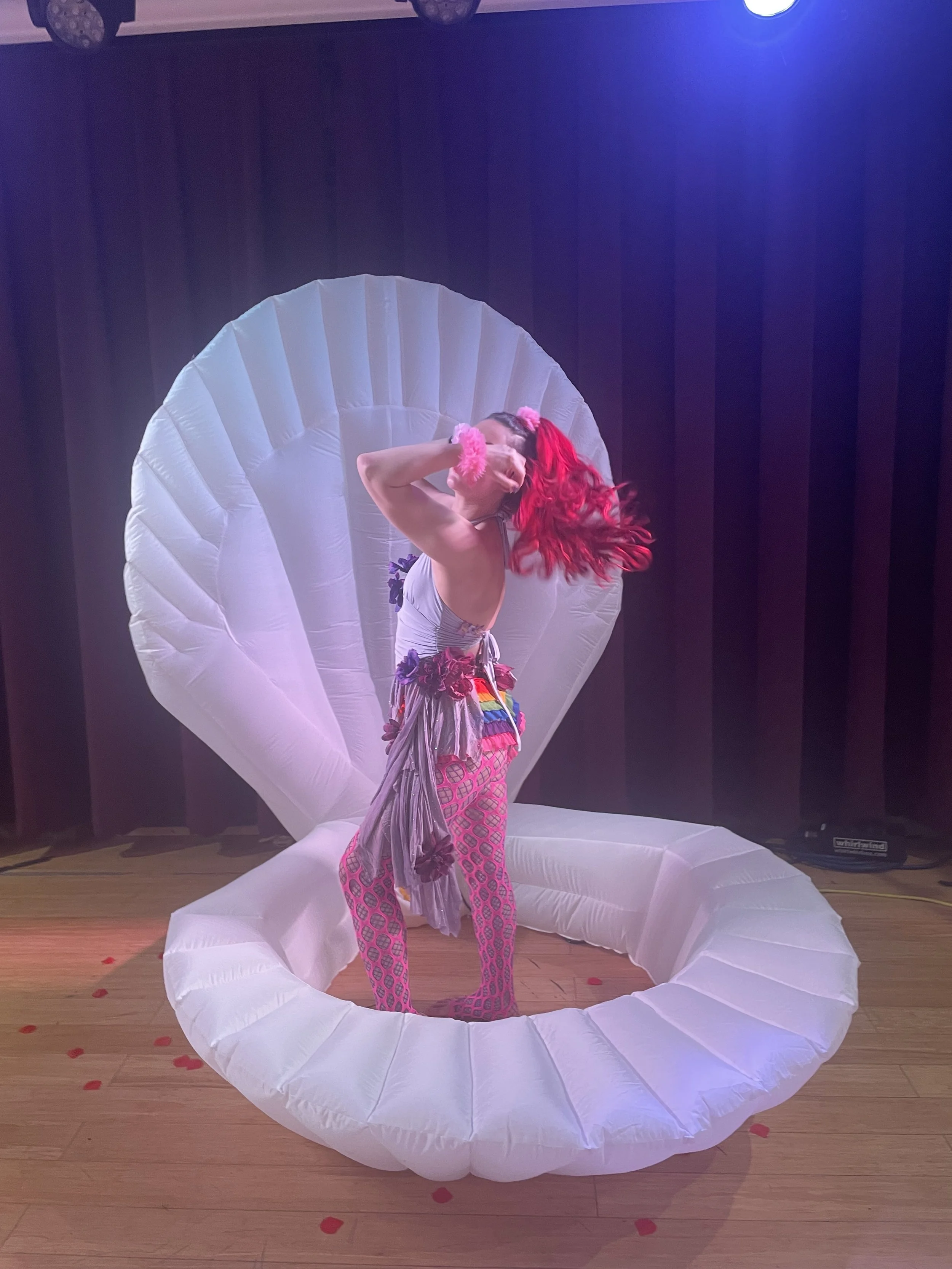 Talia Hazard performing in a pink costume before an illuminated shell