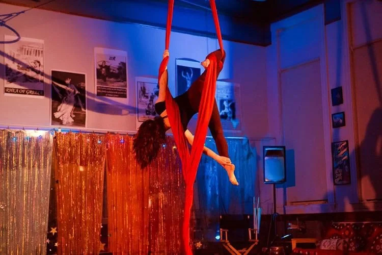 Talia Hazard performing on red aerial silks in a decorated venue