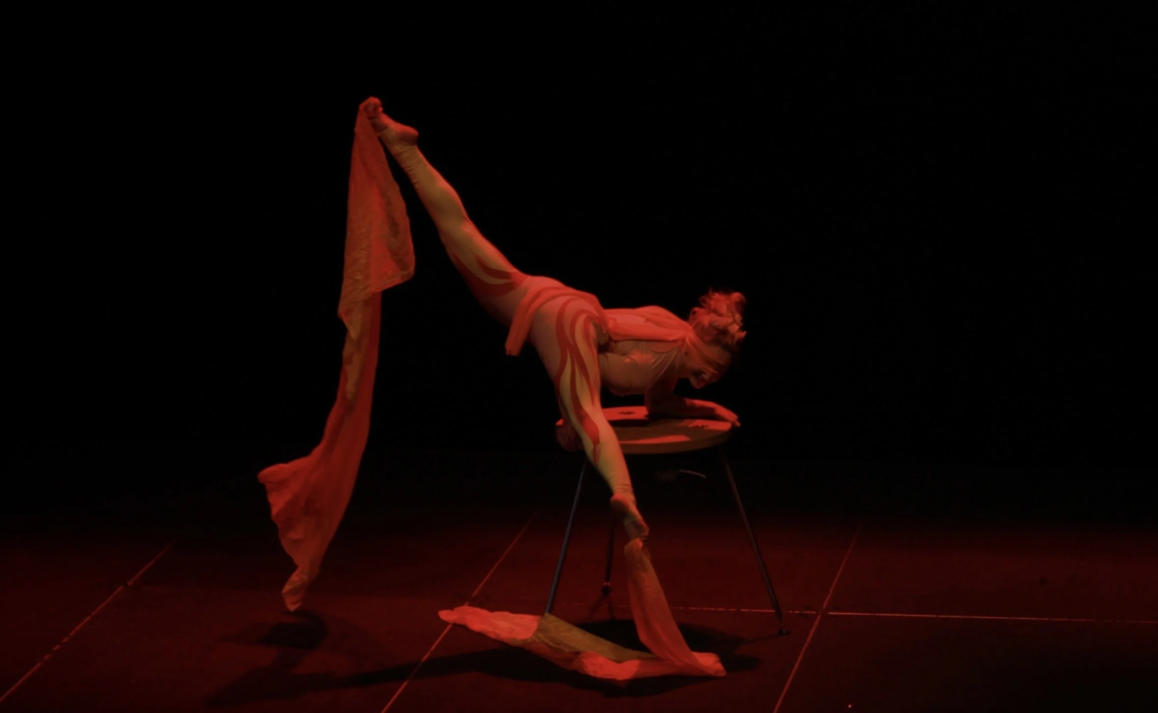 Talia Hazard extending one leg upward in a contortion pose with red fabric