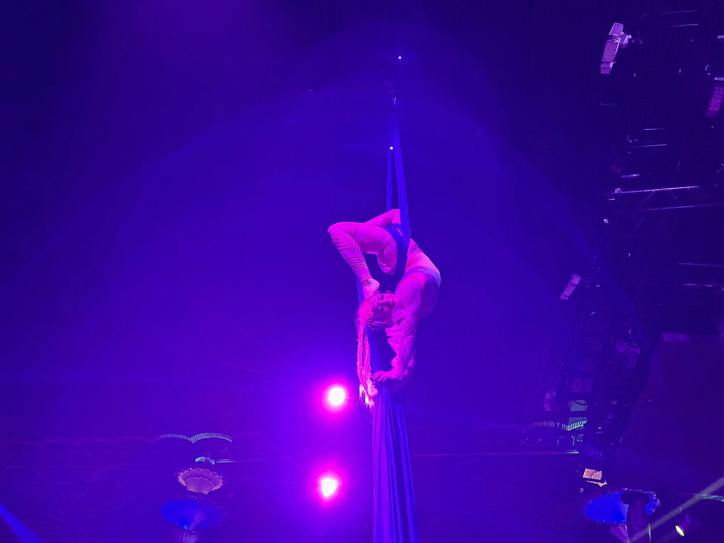 Talia Hazard suspended in an aerial pose beneath purple lights