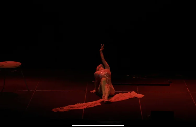 Talia Hazard in a floor split with one arm raised
