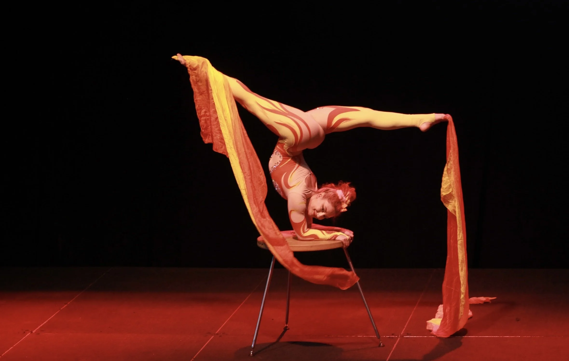 Talia Hazard balancing in a split pose with flowing red fabric