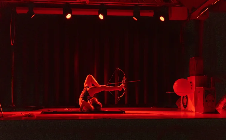 Talia Hazard performing on a stage framed by red curtains