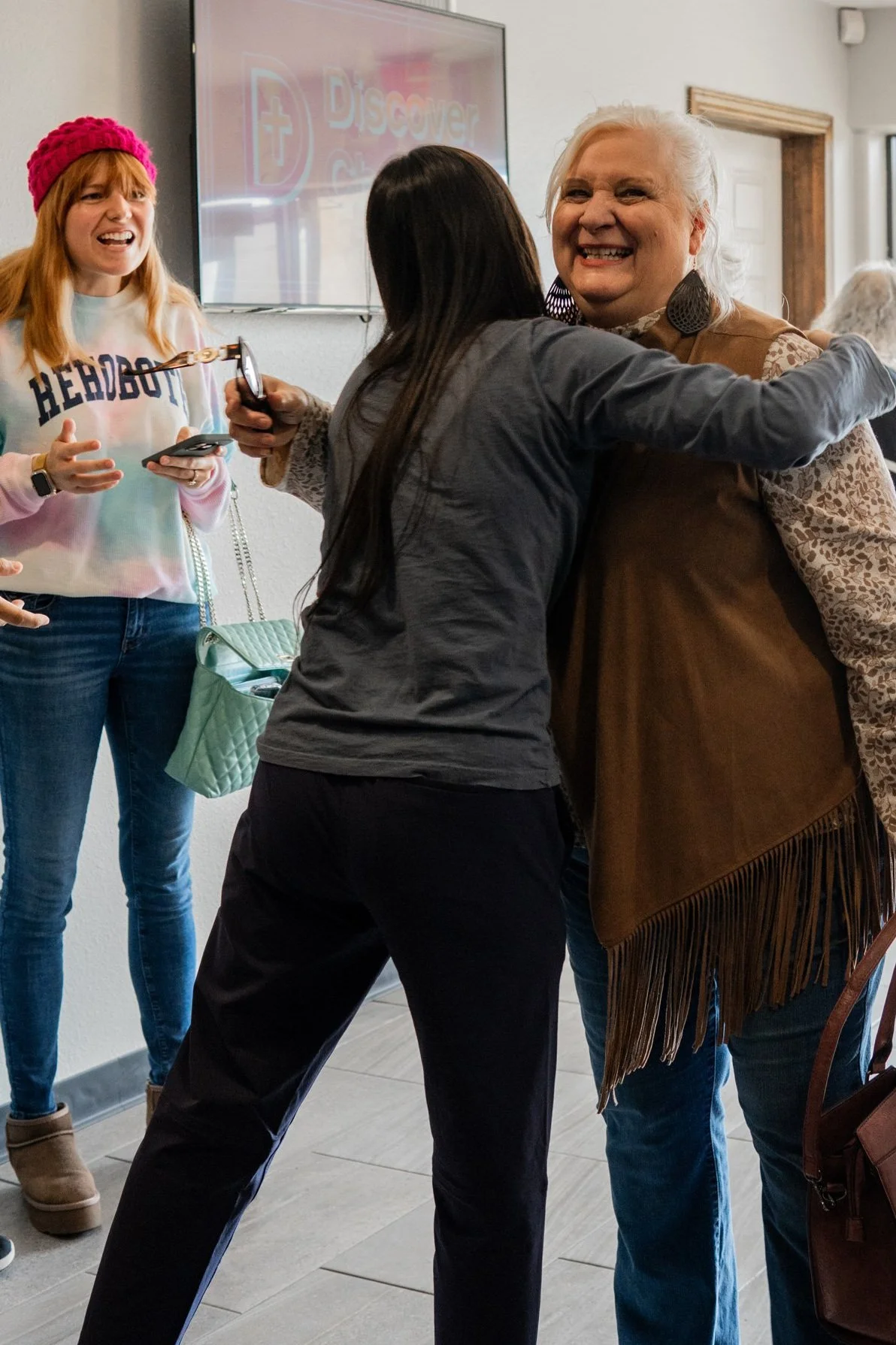 People hugging in a room with a television screen in the background