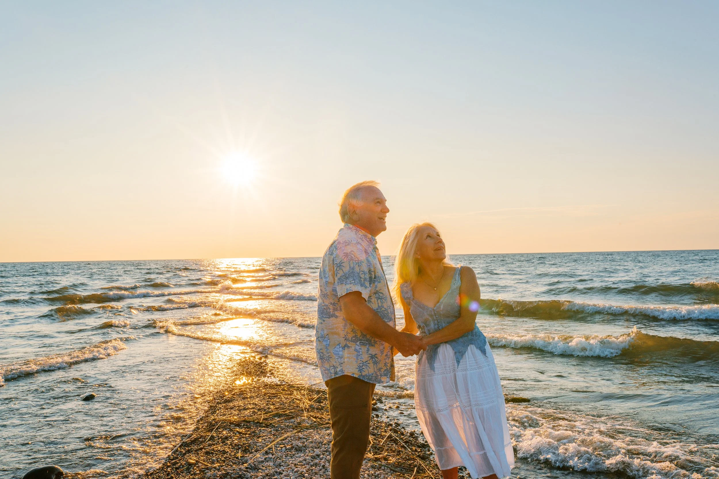 Couple laughing together on the shoreline at Long Beach Island during golden hour anniversary portraits
