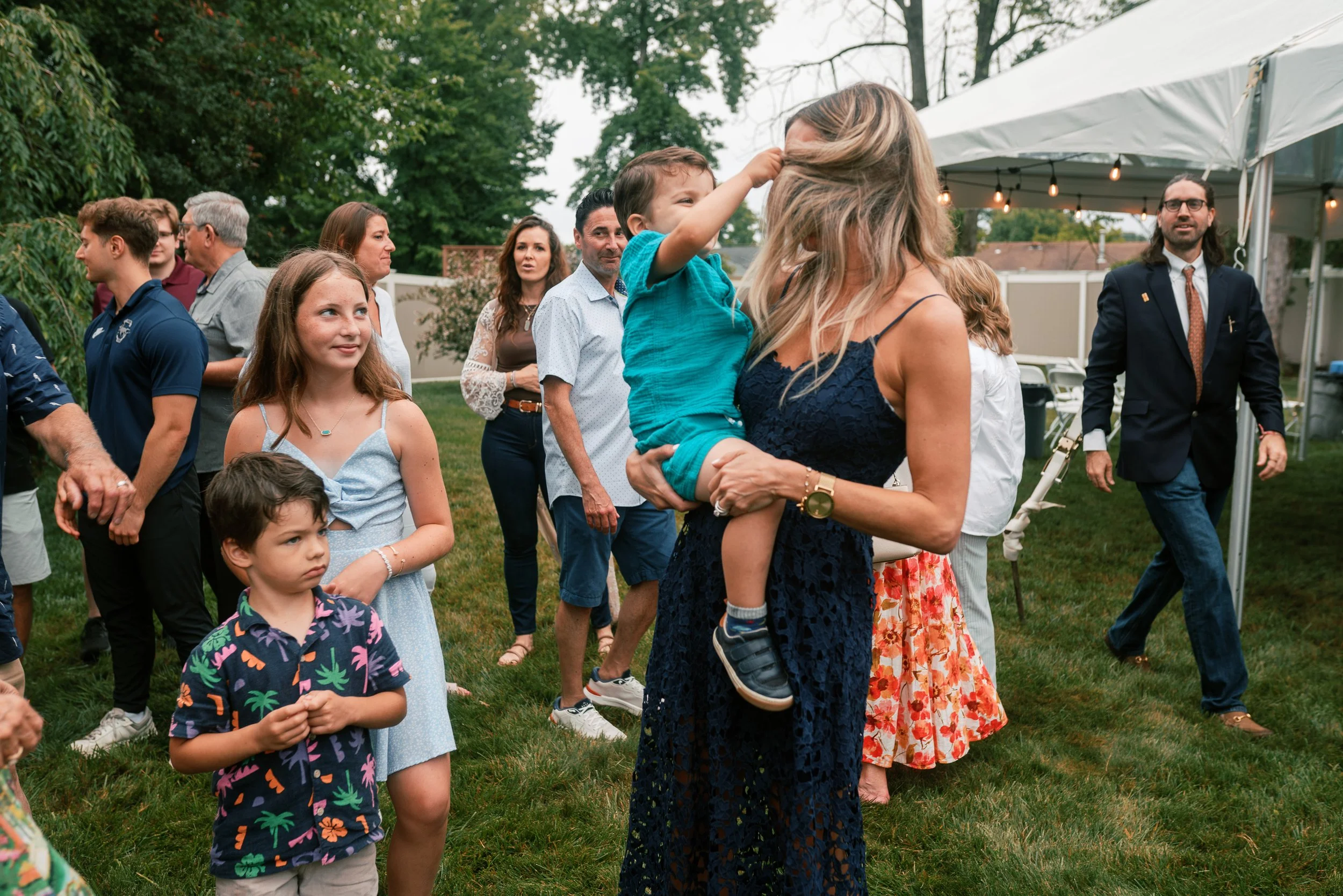 Woman holding a toddler under a string-lit tent at a South Jersey family reunion celebration