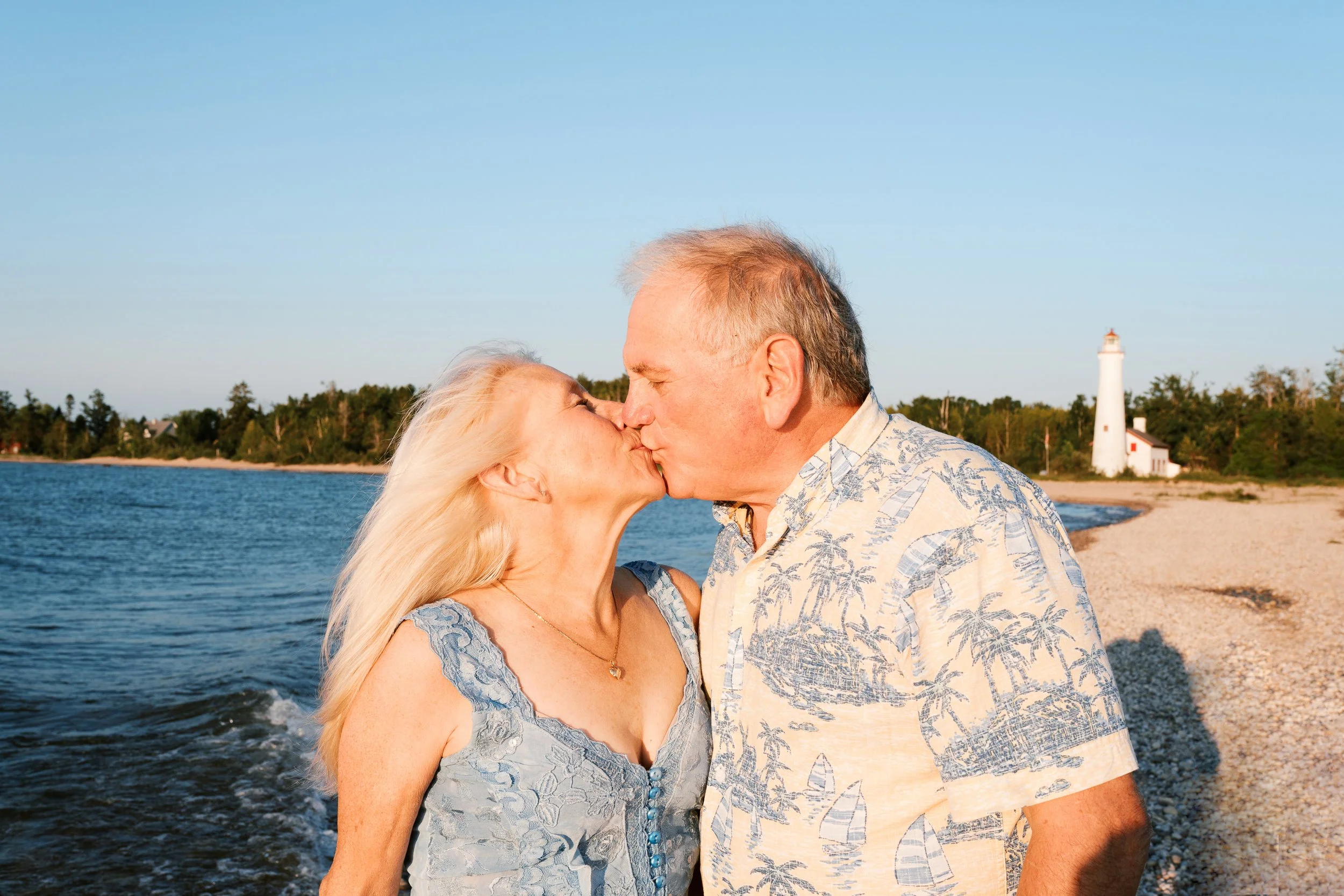 Couple kissing on the beach with a lighthouse in the background at the Jersey Shore.