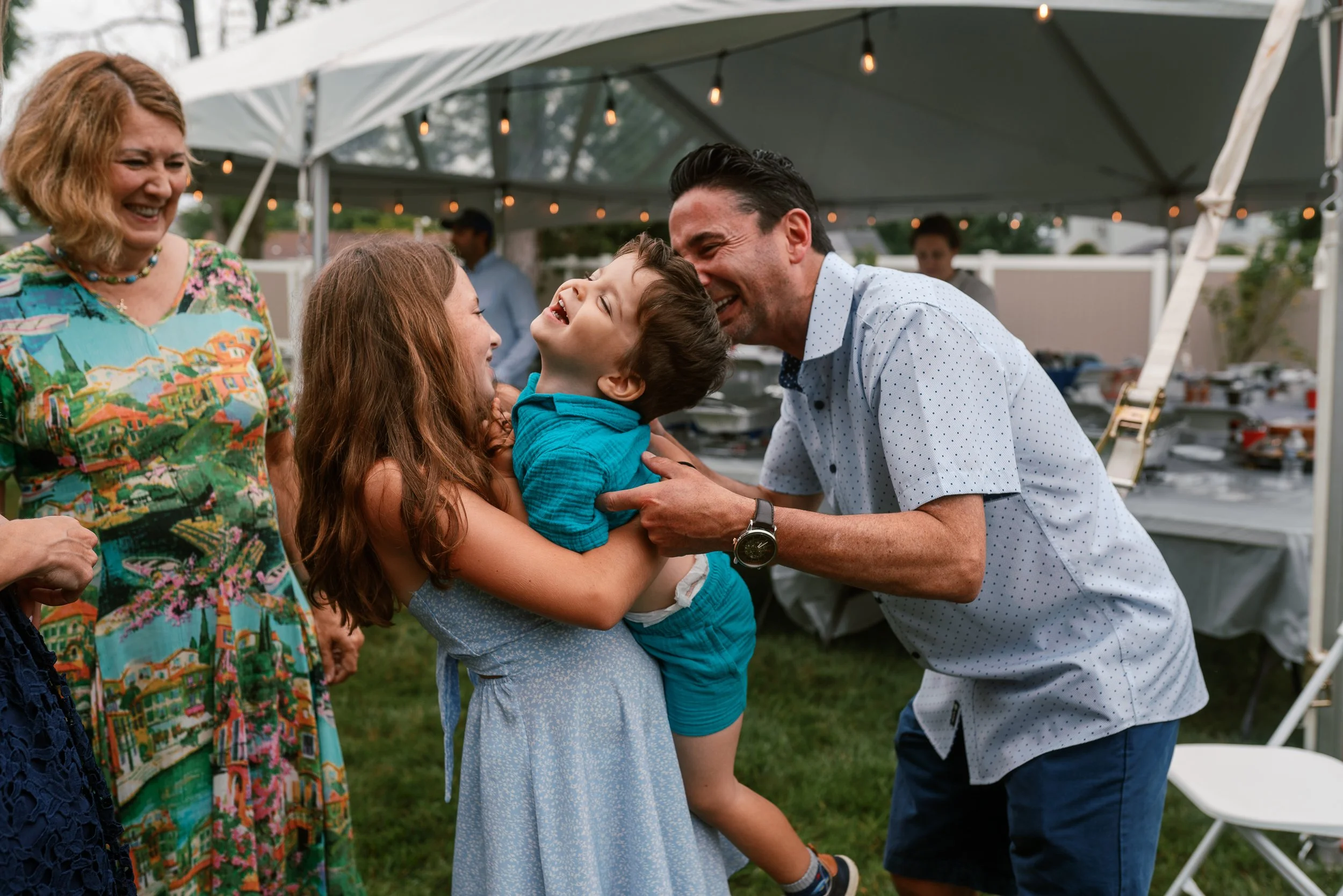 Three generations laughing together at a family reunion party in Haddonfield, NJ