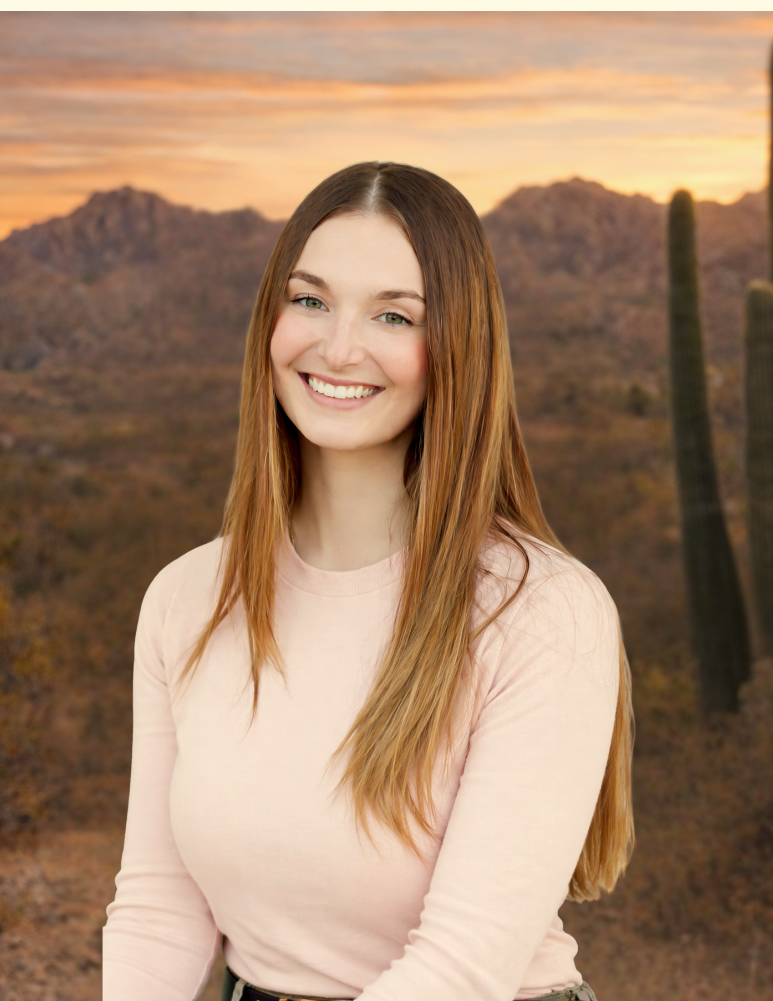 Portrait of a young woman with long red hair smiling, wearing a light pink top, with a desert landscape featuring cacti and mountains at sunset in the background.