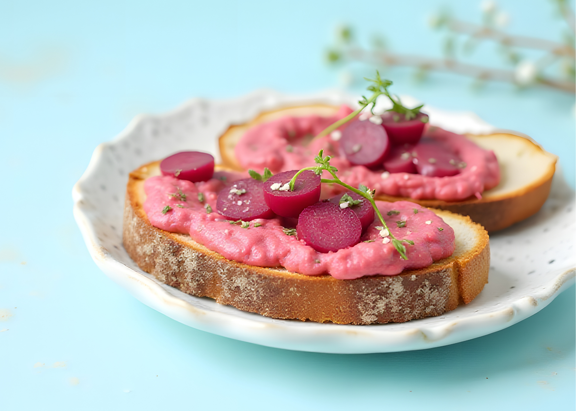 Beet hummus slathered on toast on a light colored plate, with roasted beet on top