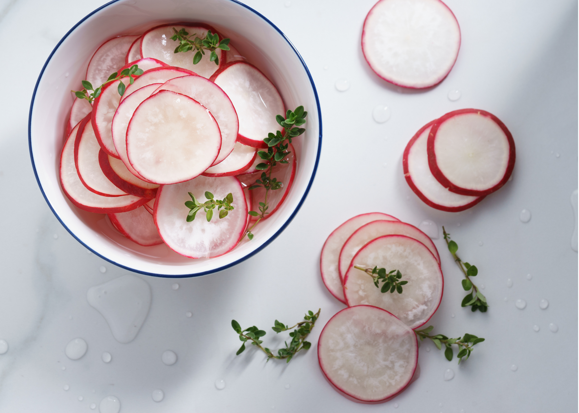 Pickled radishes in a bowl with fresh thyme