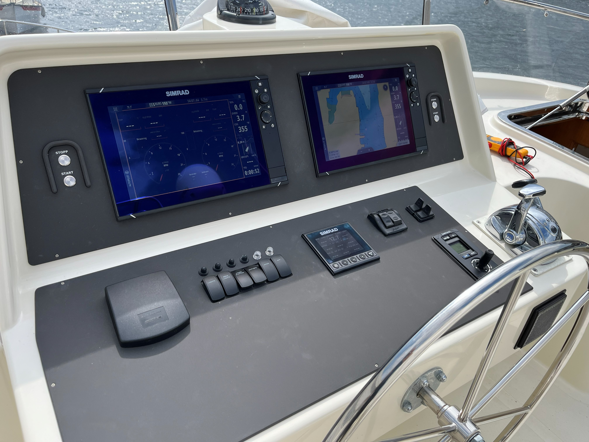 Båtens navigasjonsutstyr med to SIMRAD skjermbilder som viser kart og instrumenter på en båtkontrollpanel.