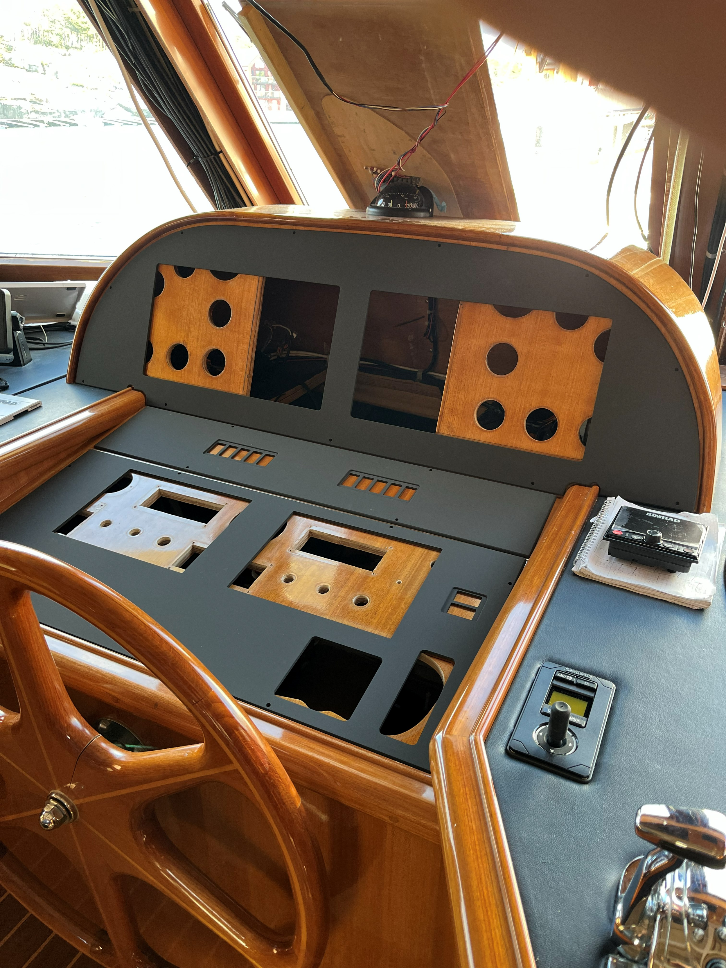 Trebåtens cockpit under oppussing, med ratt, instrumentpanel, kompass, ledninger og åpninger for marineelektronikk.