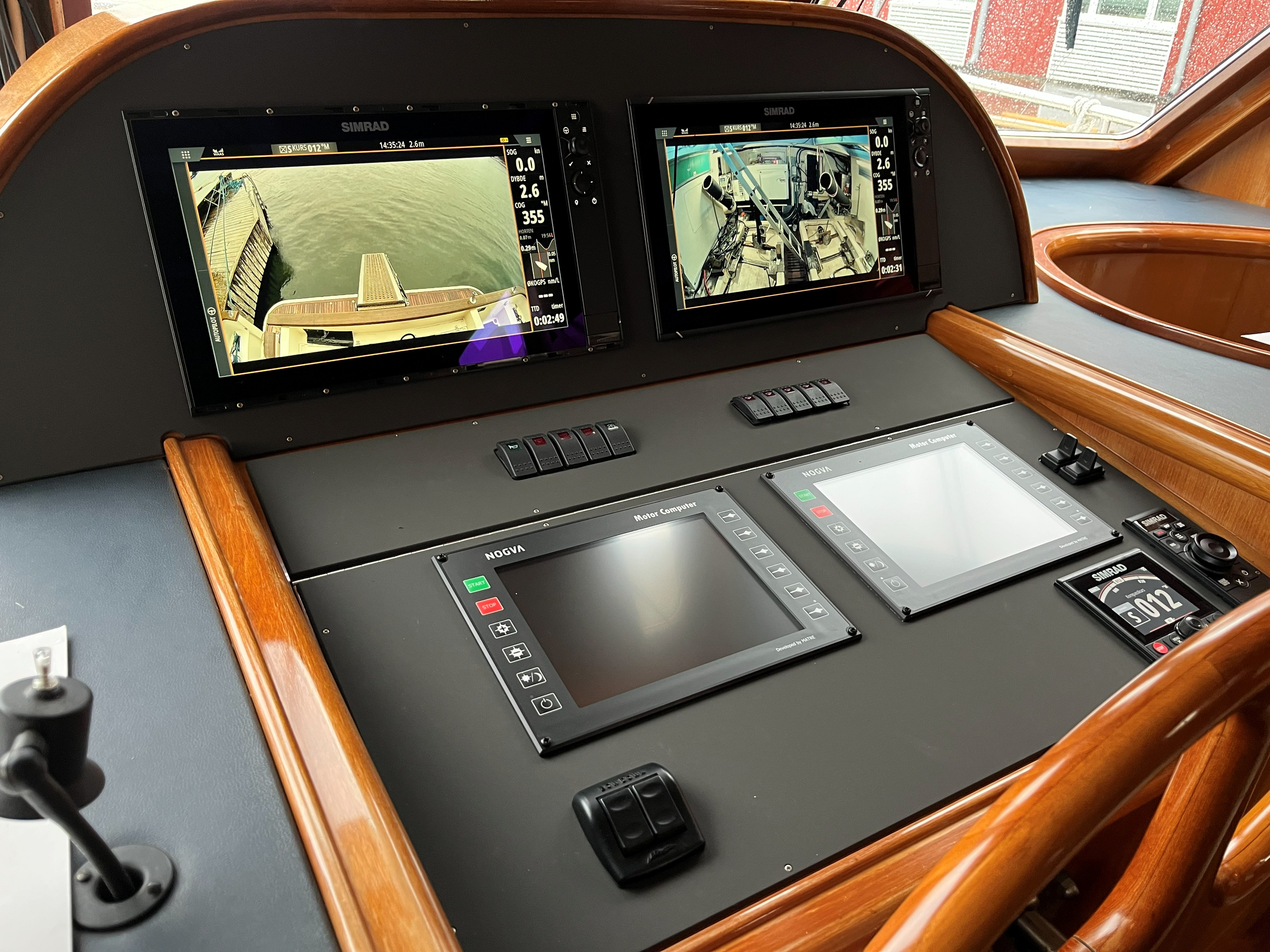 Styrekonsoll på båt med Simrad-navigasjonsskjermer, motordisplay og kontrollbrytere