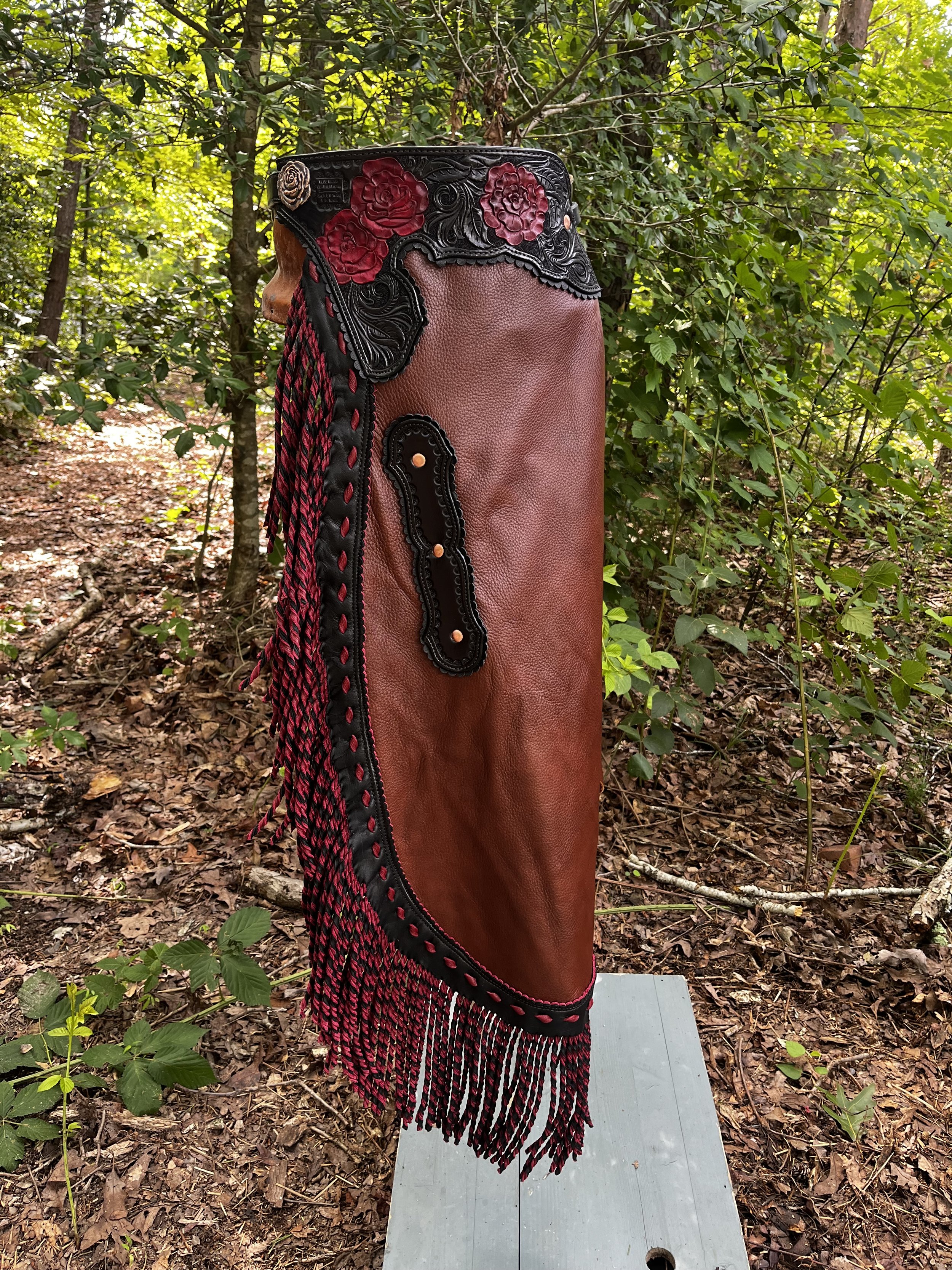 A decorative sculpture of a punching bag with intricate floral carved design, mounted on a stand in a wooded outdoor setting.