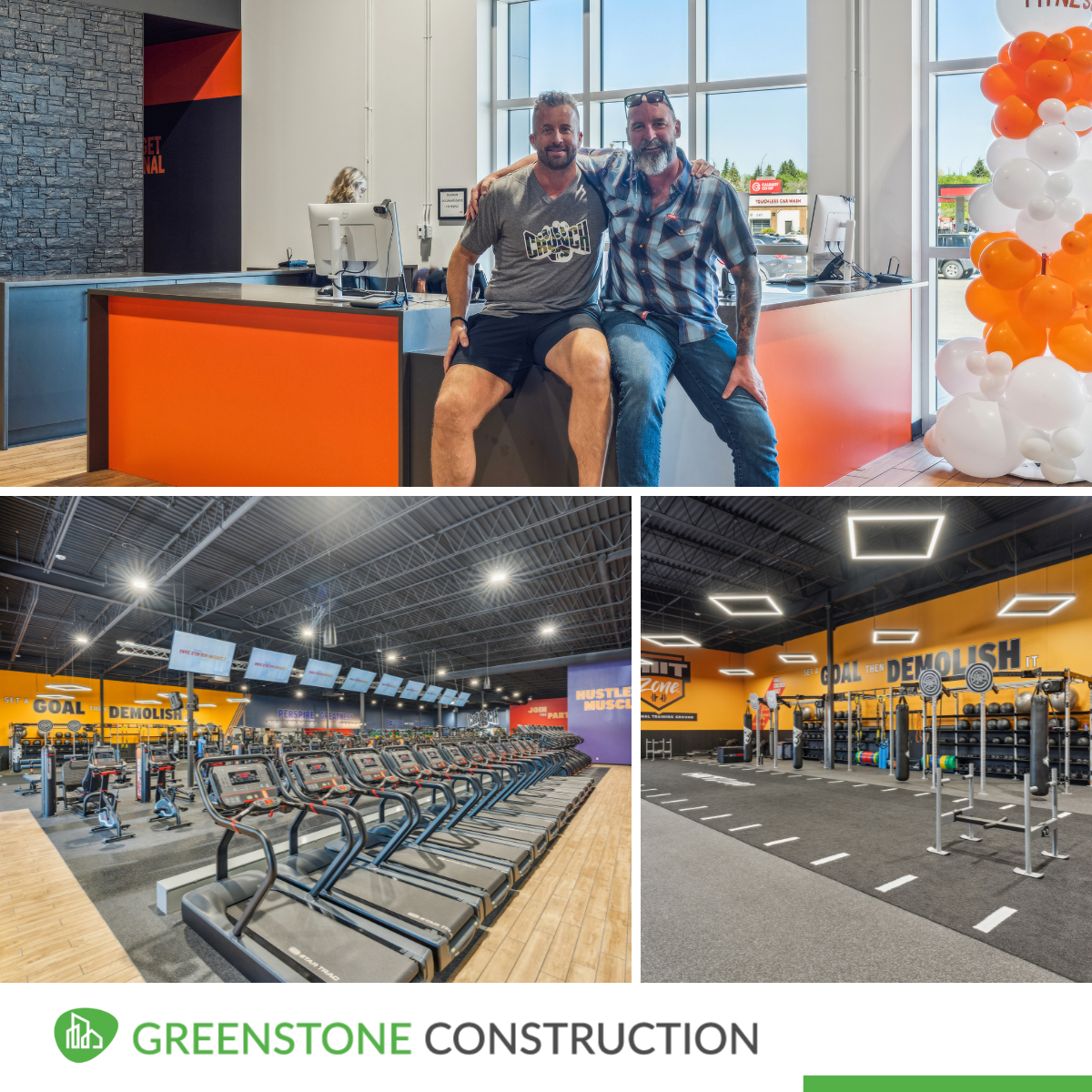 Two men sitting on a reception counter in a gym, smiling with arms around each other. Inside a fitness center with cardio machines, weightlifting equipment, and motivational wall signs.