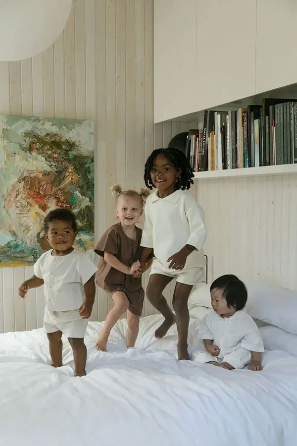 Four children are playing on a bed in a bedroom.