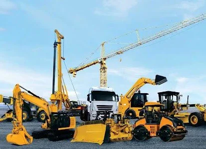 Construction equipment including excavators, bulldozers, and a dump truck on a construction site with a blue sky.