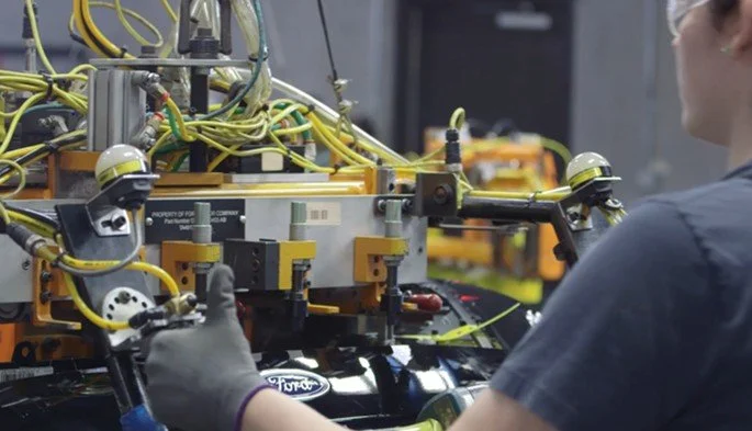 A person working on a complex robotic system with multiple wires and mechanical parts.
