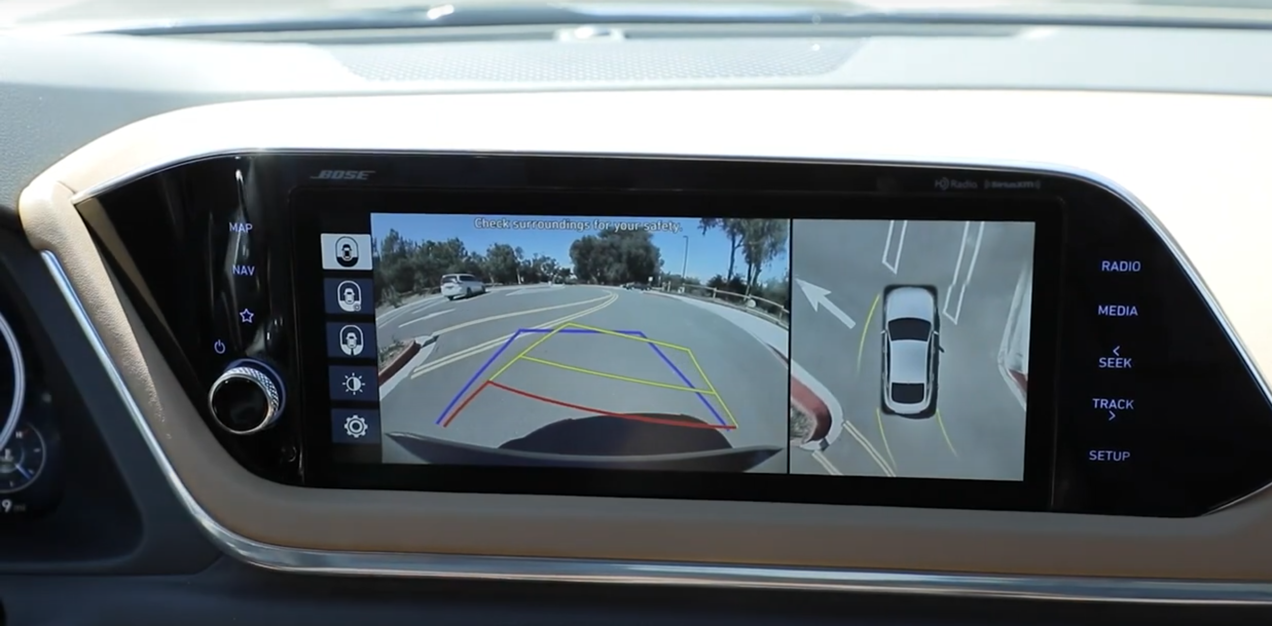 Car dashboard screen displaying rearview and overhead camera views for parking assistance.