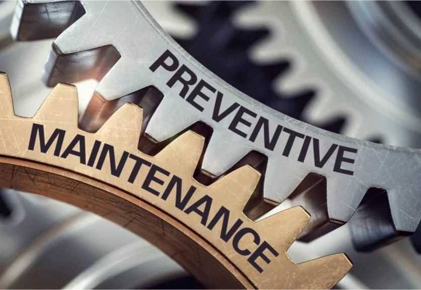 Close-up of metal gears with the words "Preventive" on the silver gear and "Maintenance" on the bronze gear.