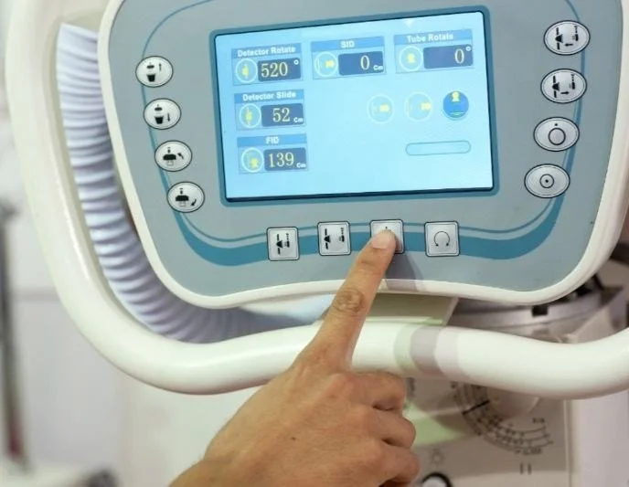 Close-up of a person pressing a button on a medical device control panel with a touchscreen display showing various settings.