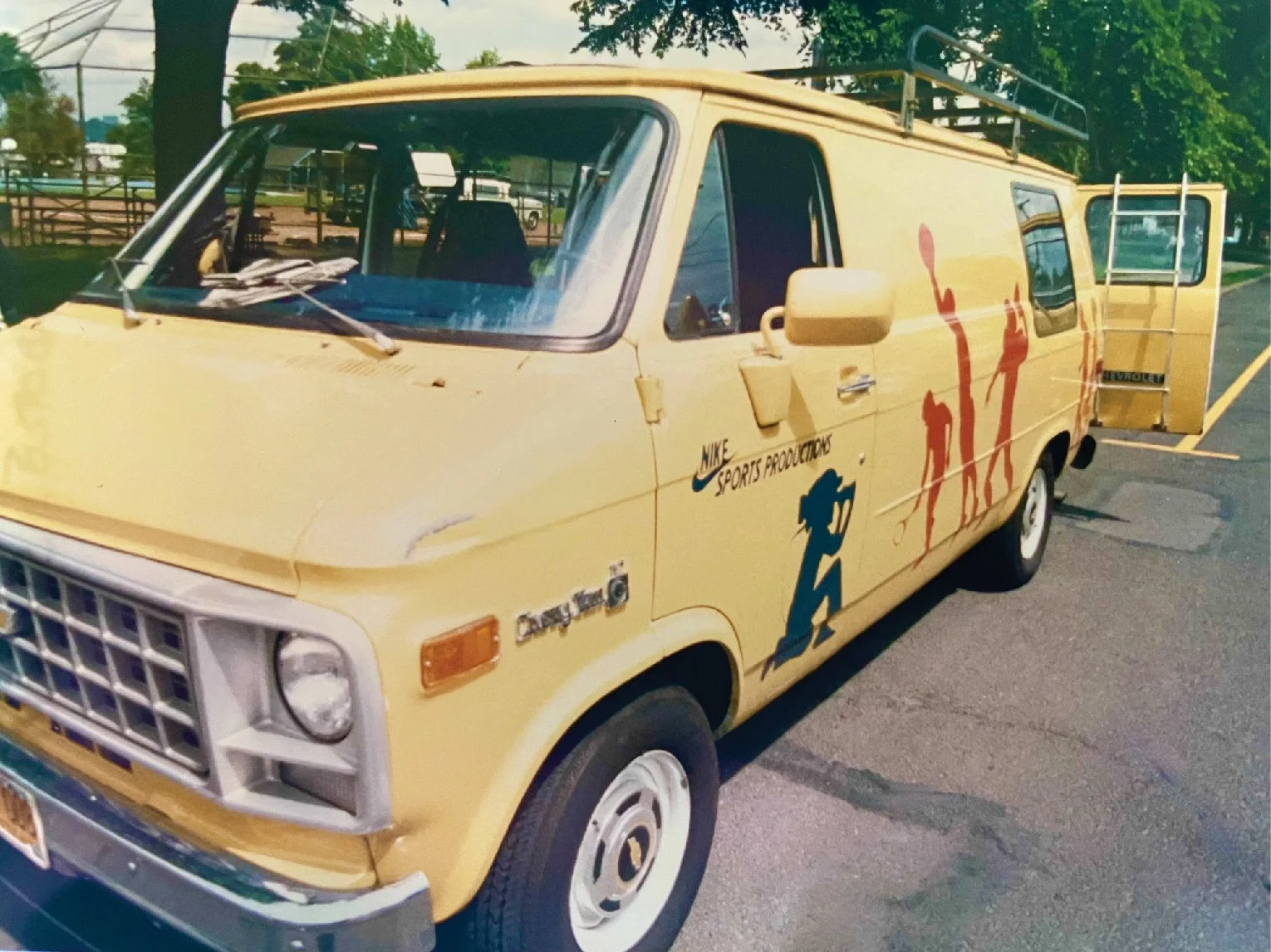 The original Nike Design van. A yellow van with a rack on top and silhouettes a person video tapping and various athletes playing sports.