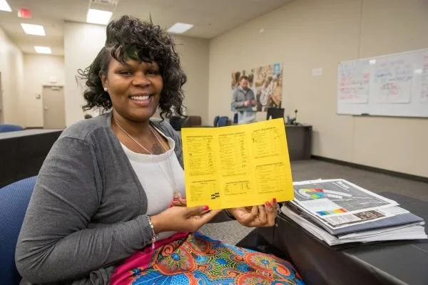 woman holding trifold showing results of class.