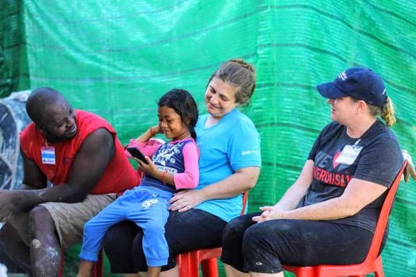 Family and workers sitting at a build site