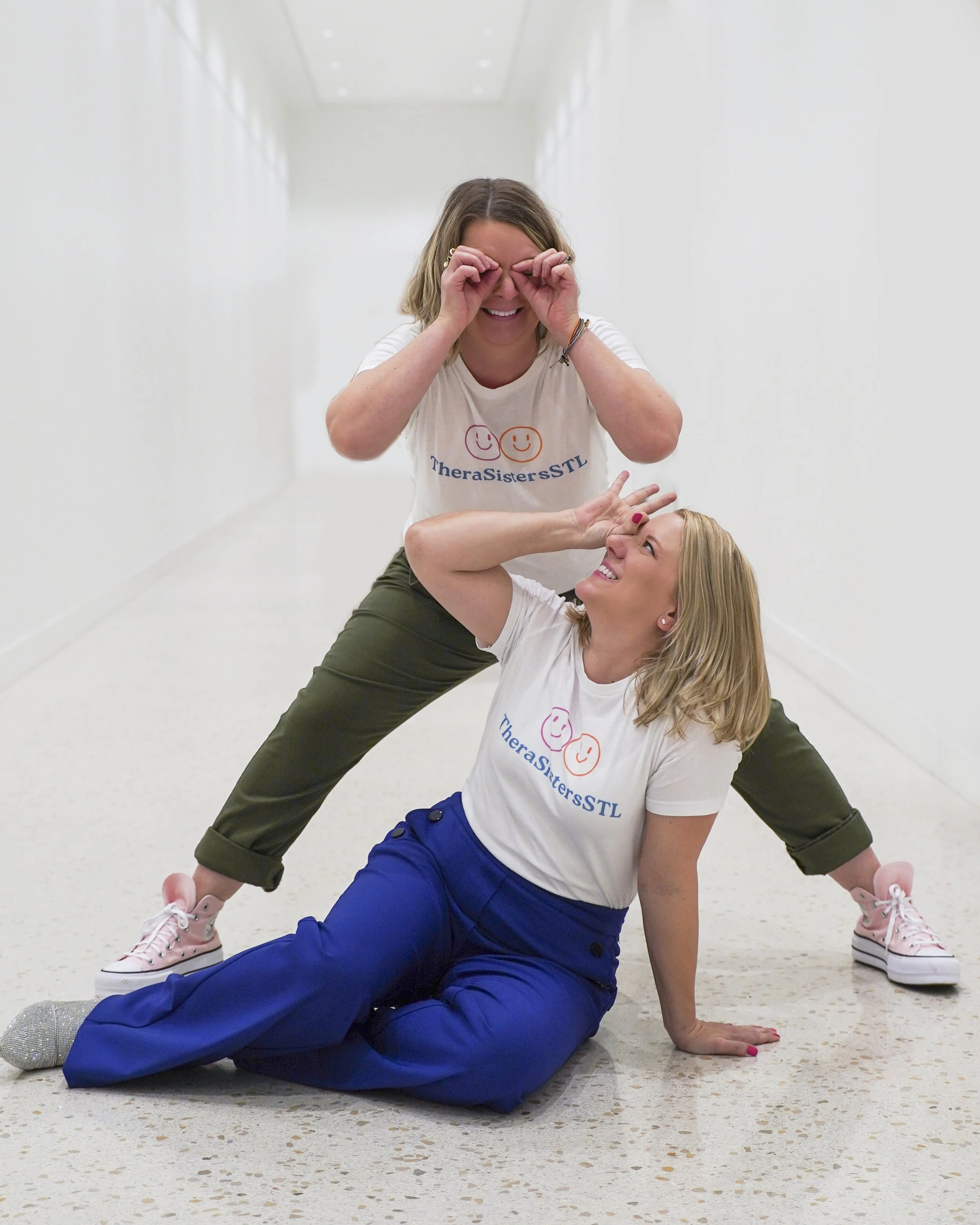 TheraSistersSTL's Amy and Katheryn in a playful pose, embodying laughter and joy in the self-care journey.