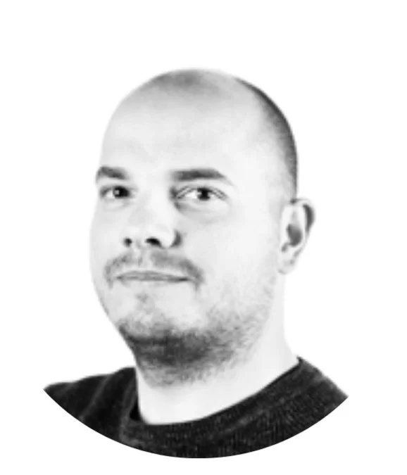 Black and white portrait of a man with short hair and a slight smile, wearing a dark shirt.