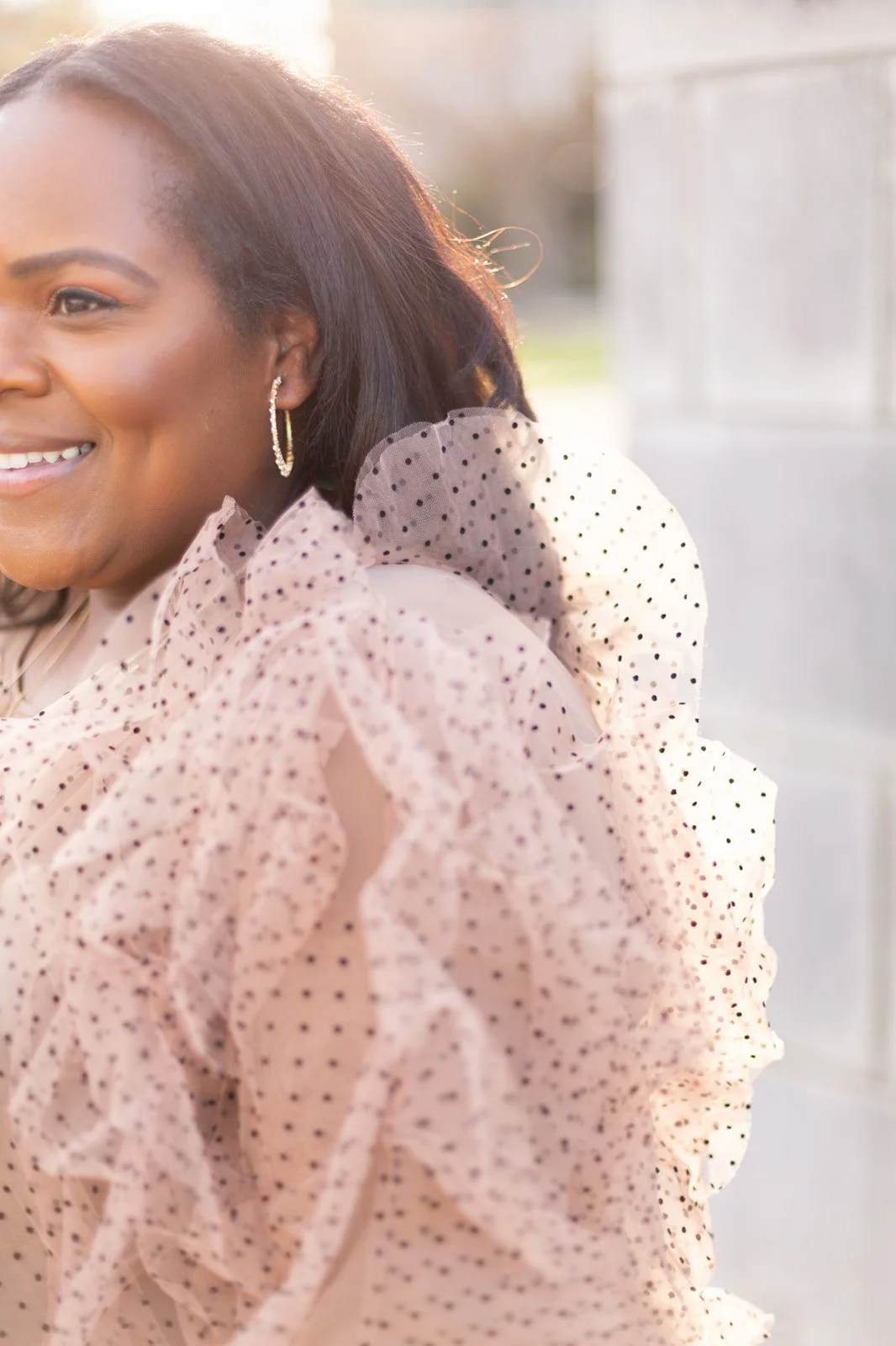 Woman smiling in ruffled polka dot blouse