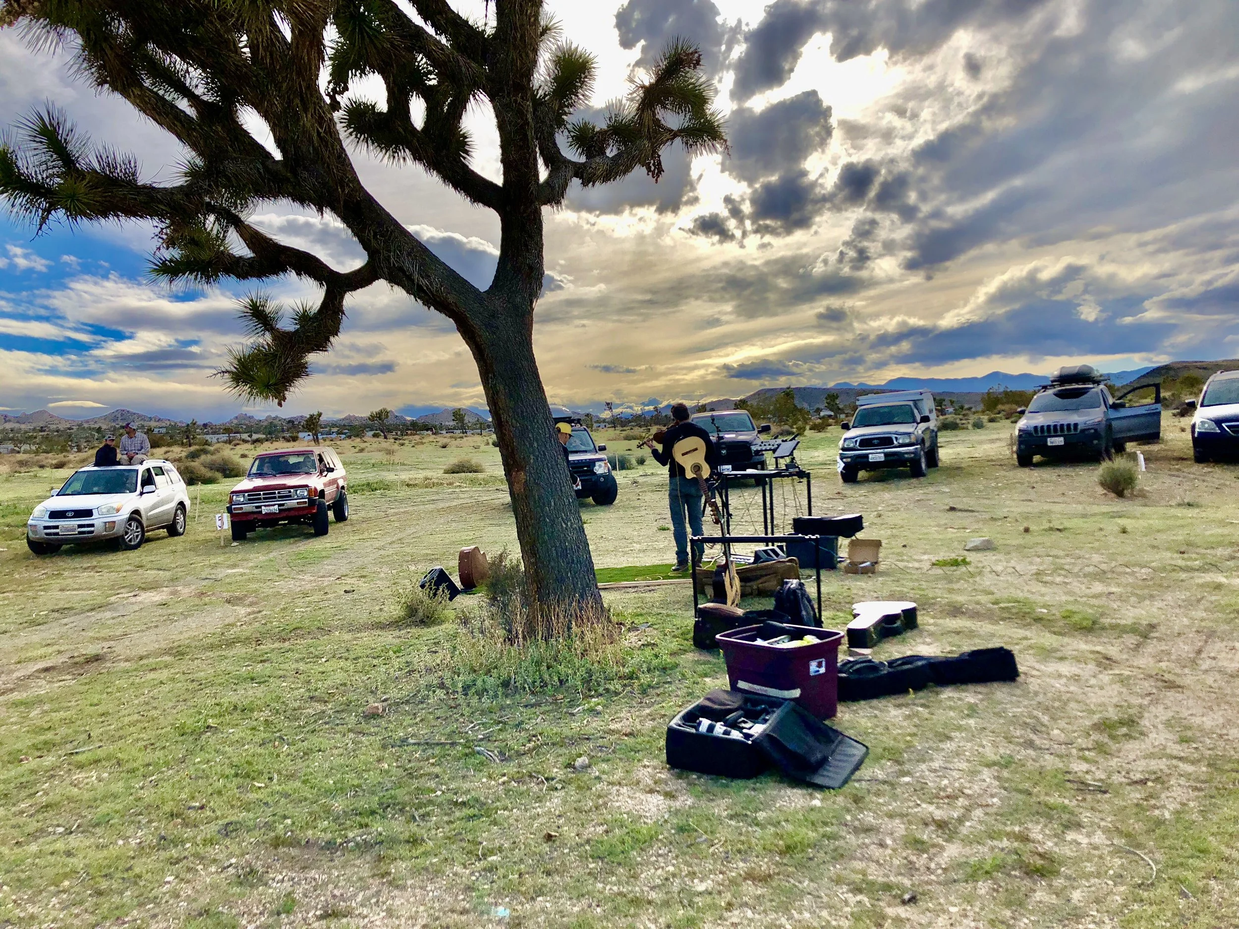 two musicians perform in front of a small group of people sitting in their cars