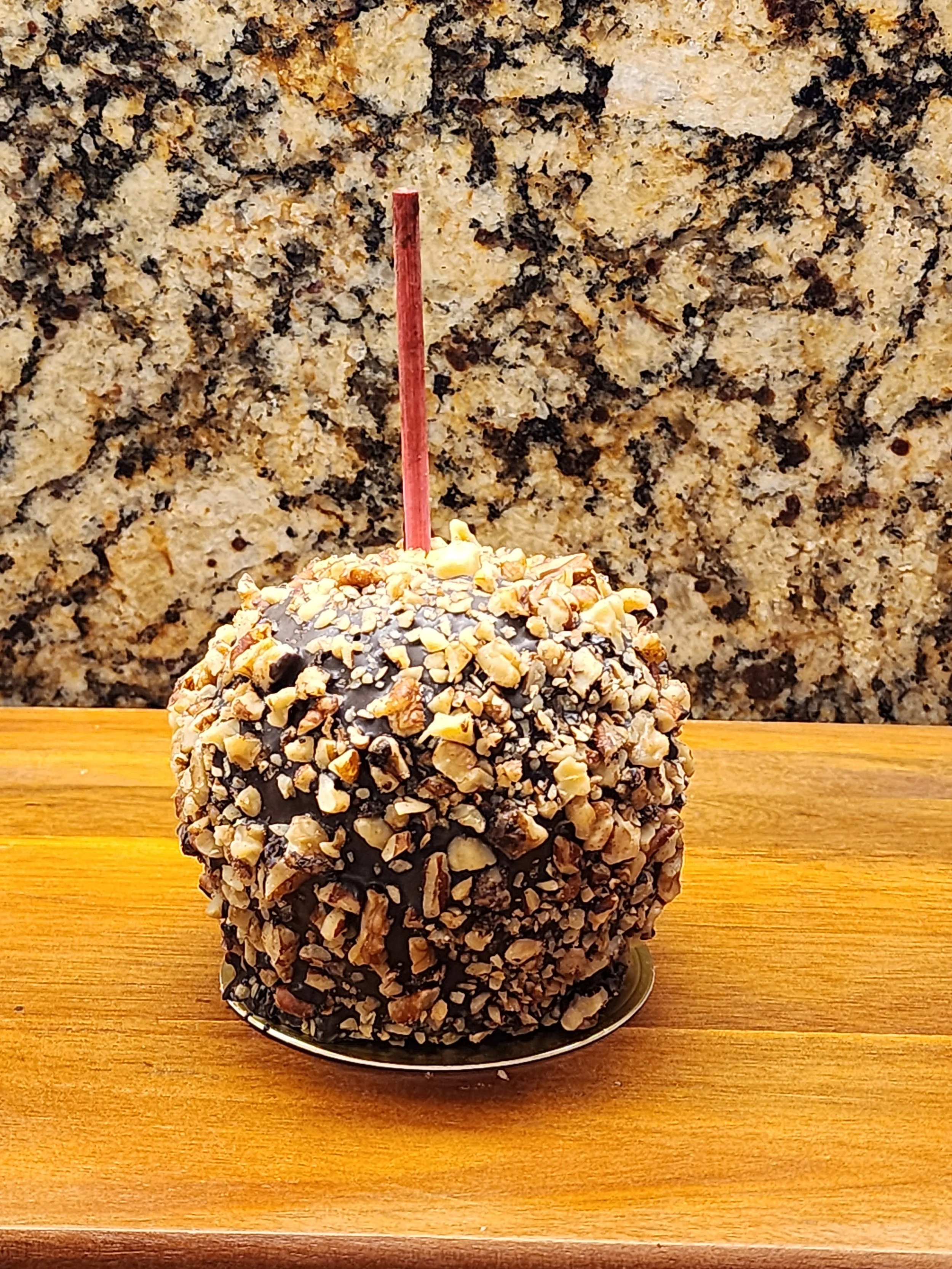 A caramel apple covered in chopped nuts.