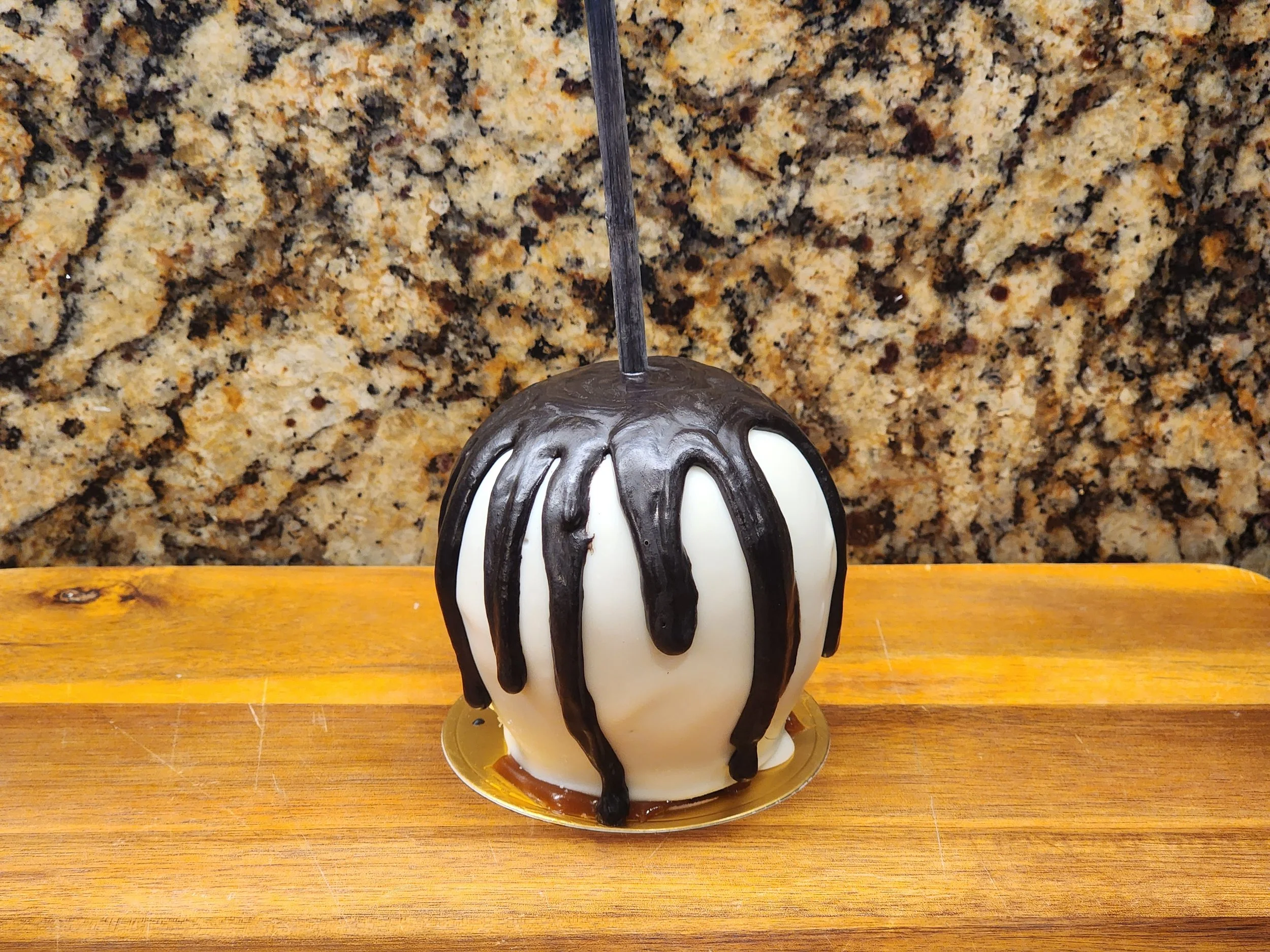 Dripping black chocolate on a white chocolate-dipped caramel apple.jpg