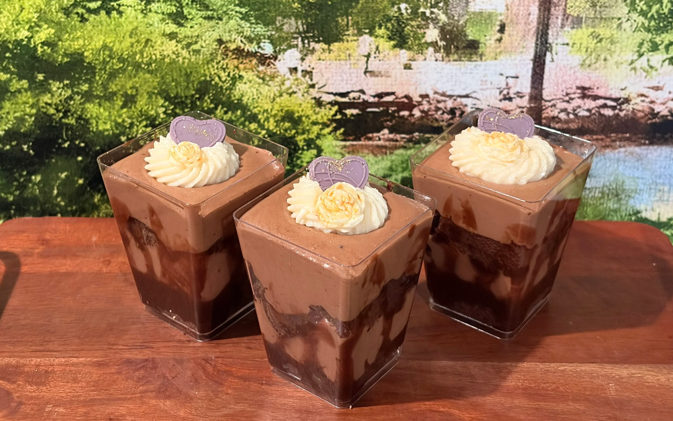 Espresso chocolate mousse cups garnished with a lavendar heart & gilded cream rose, on a wooden serving tray. 