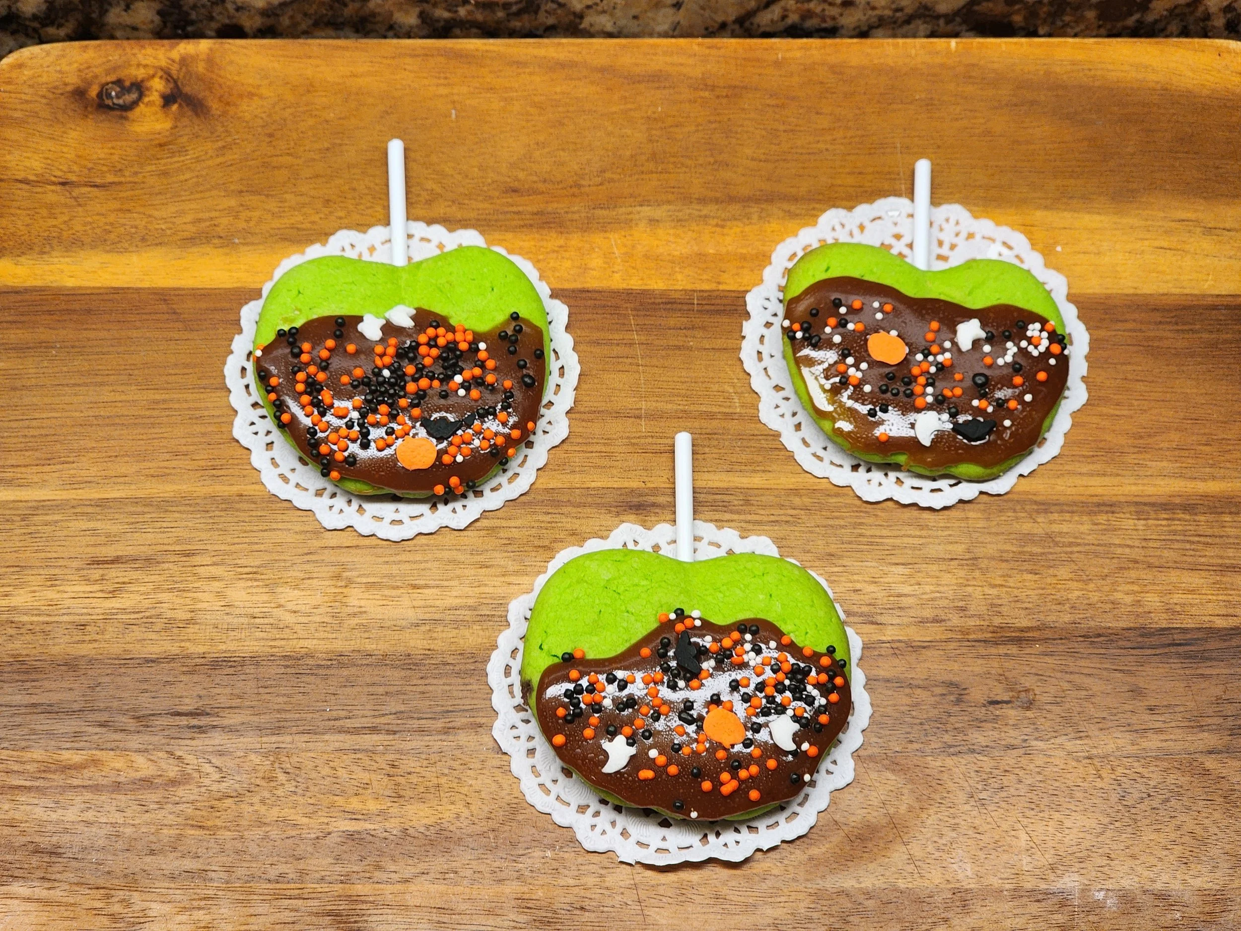Caramel apples dipped in green and dark chocolate with Halloween-themed sprinkles