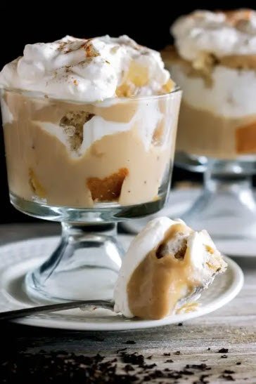 A Spiced Chai mousse dessert cup with layers of cake and cream, drizzled with caramel sauce and topped with whipped cream.