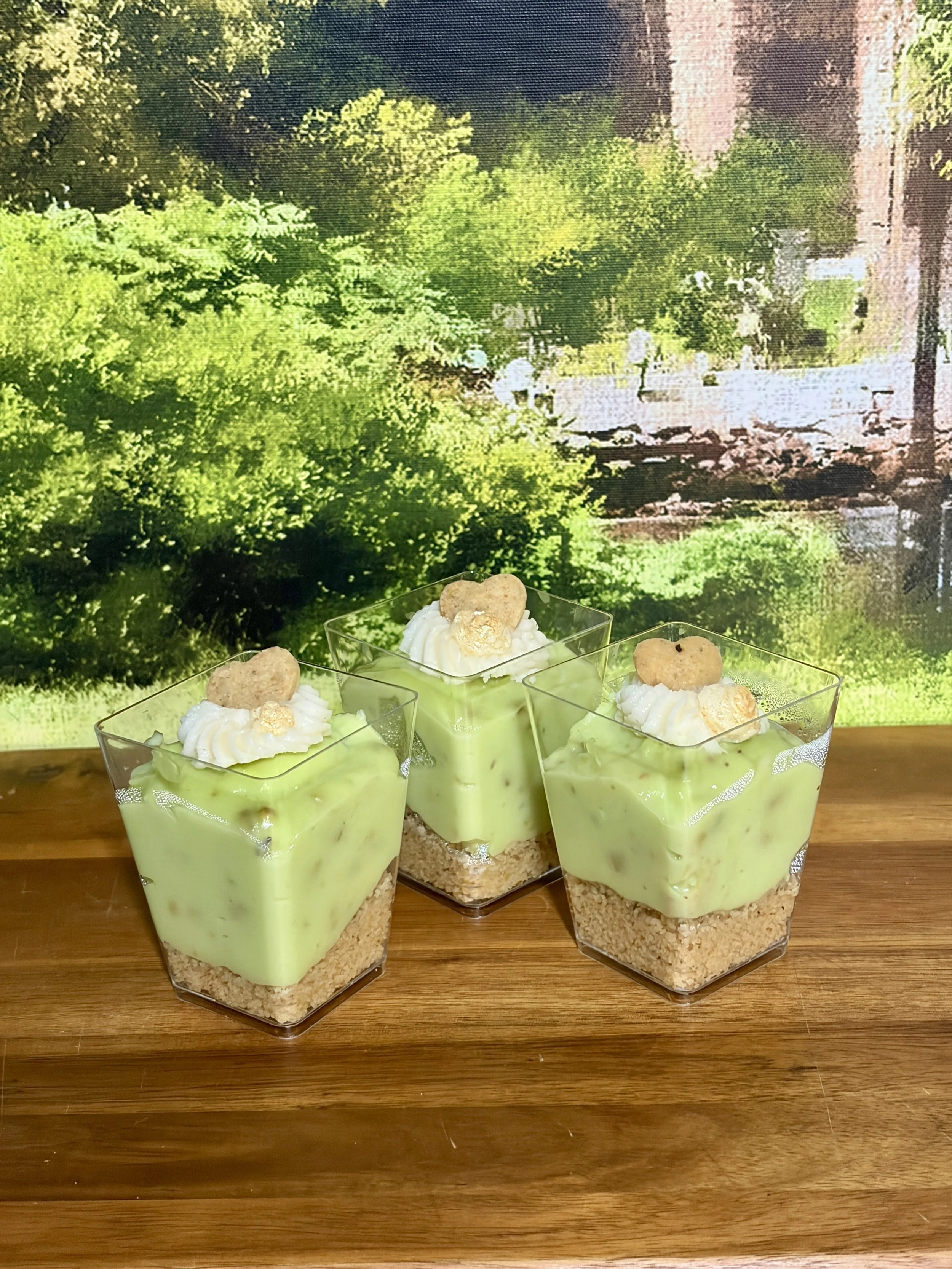 Pistachio cream dessert cups topped with heart-shaped pistachio cookie.