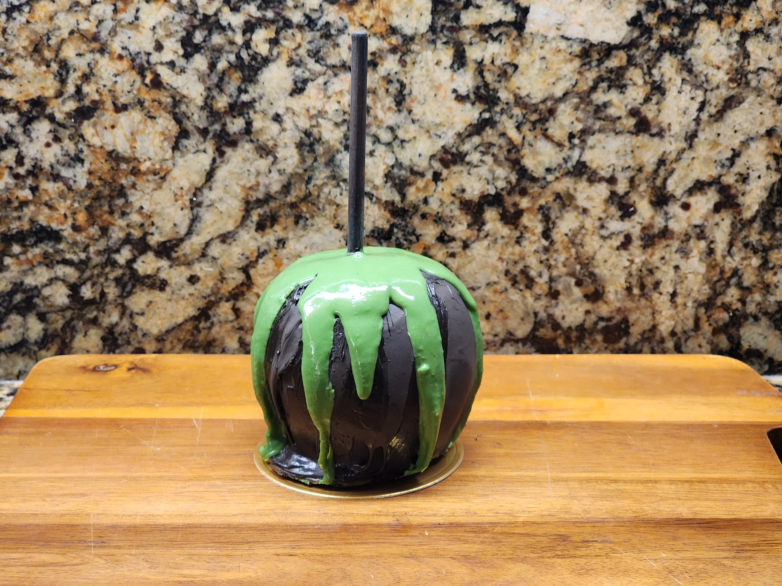Dripping green chocolate on a black chocolate caramel apple.jpg
