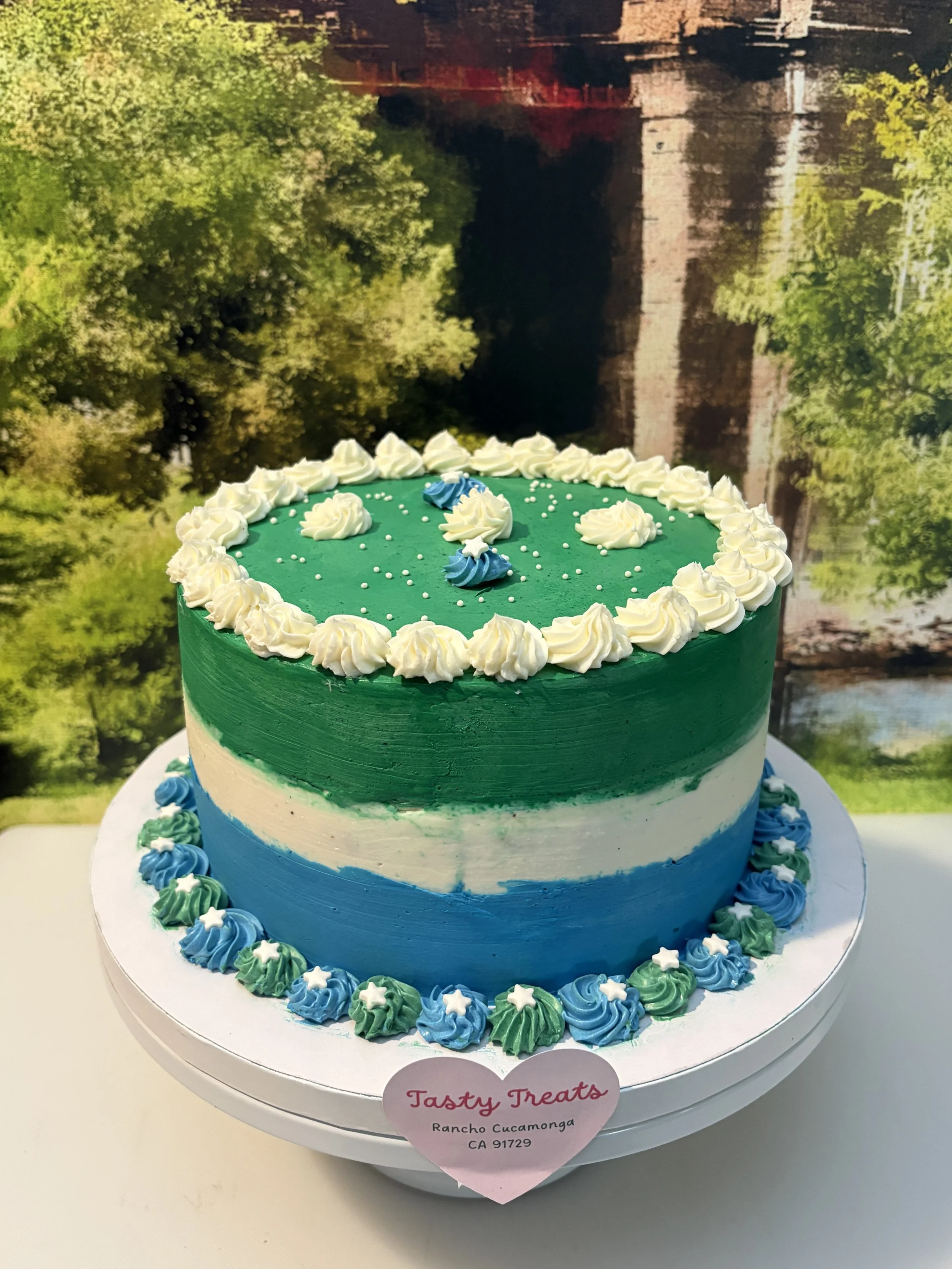 Two-tone green and white 8-inch cake with a striped base and piped white floral top design