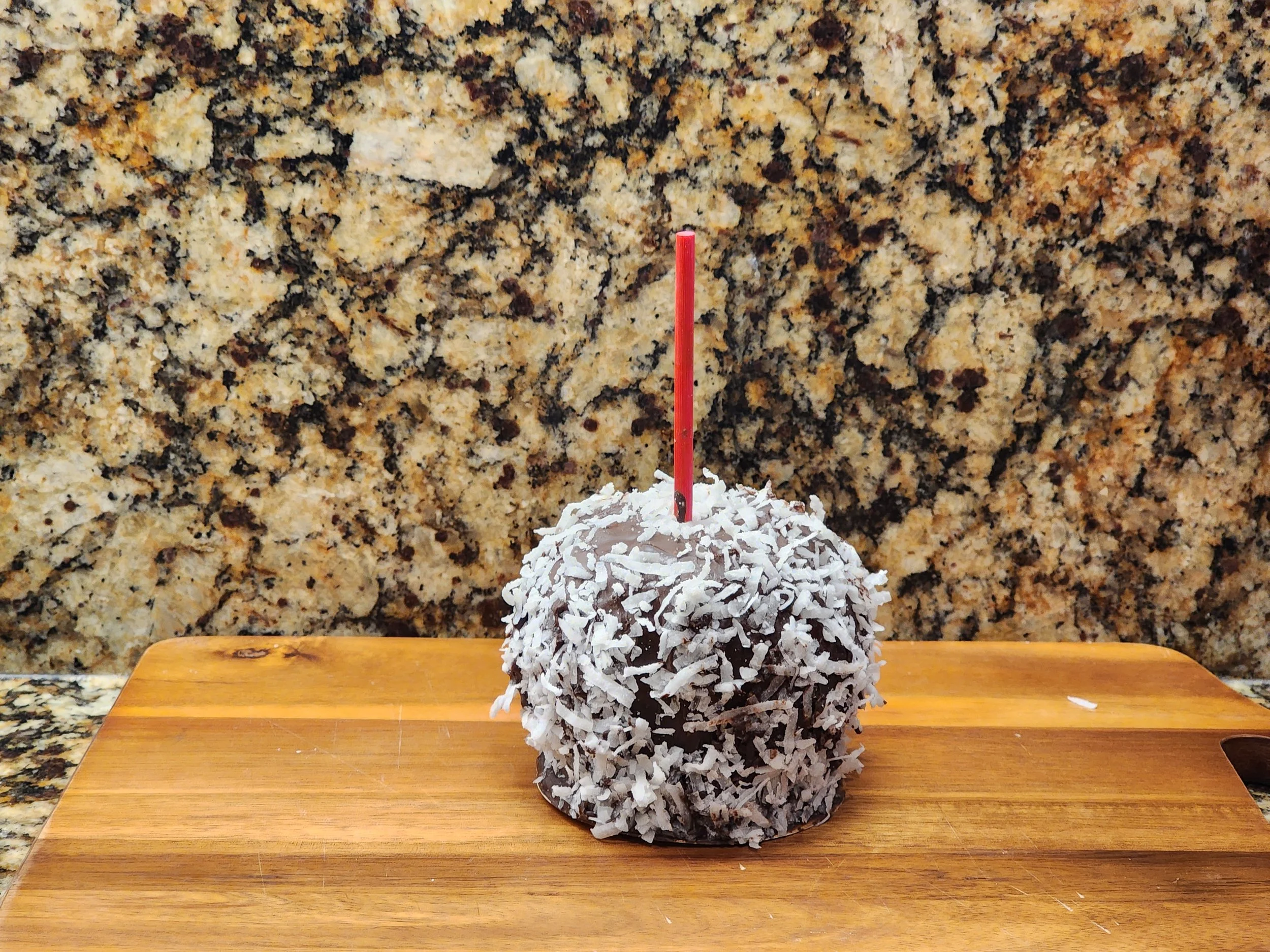 A caramel apple covered in white and silver sanding sugar.