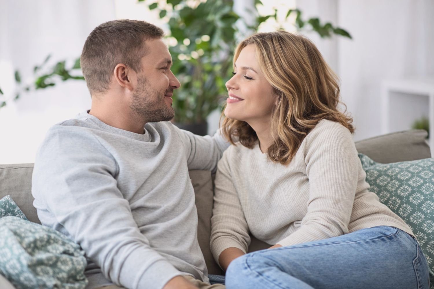 Couple sitting together on a couch discussing shared finances and budgeting decisions.