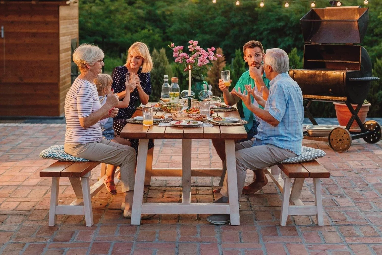 Affluent family enjoying dinner together outdoors at sunset, symbolizing multi-generational wealth and legacy planning.