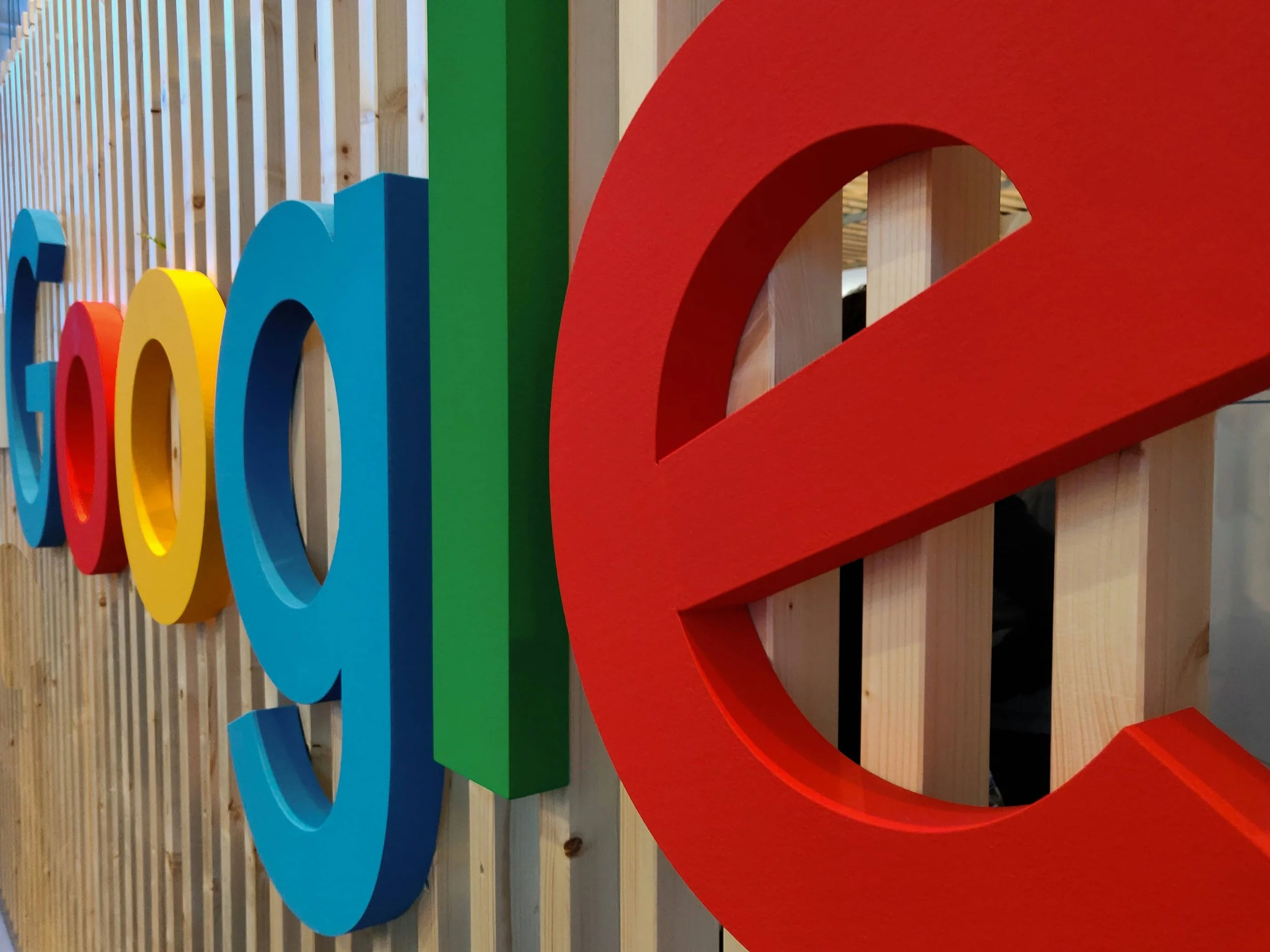 3D Google sign on wooden wall, in the colors blue, red, yellow and green.