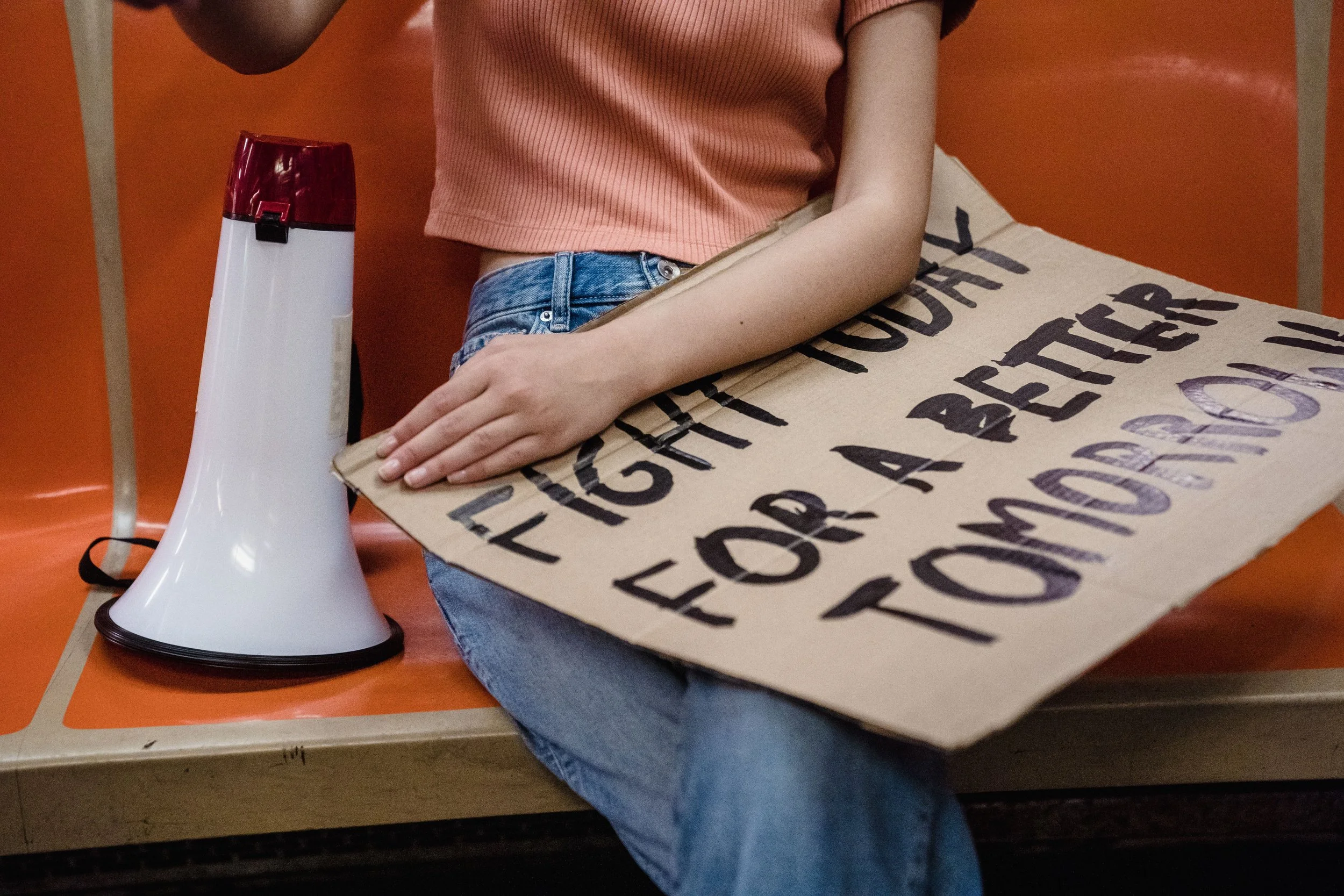 Person holding a megaphone and a cardboard sign reading “Fight for a better tomorrow.”