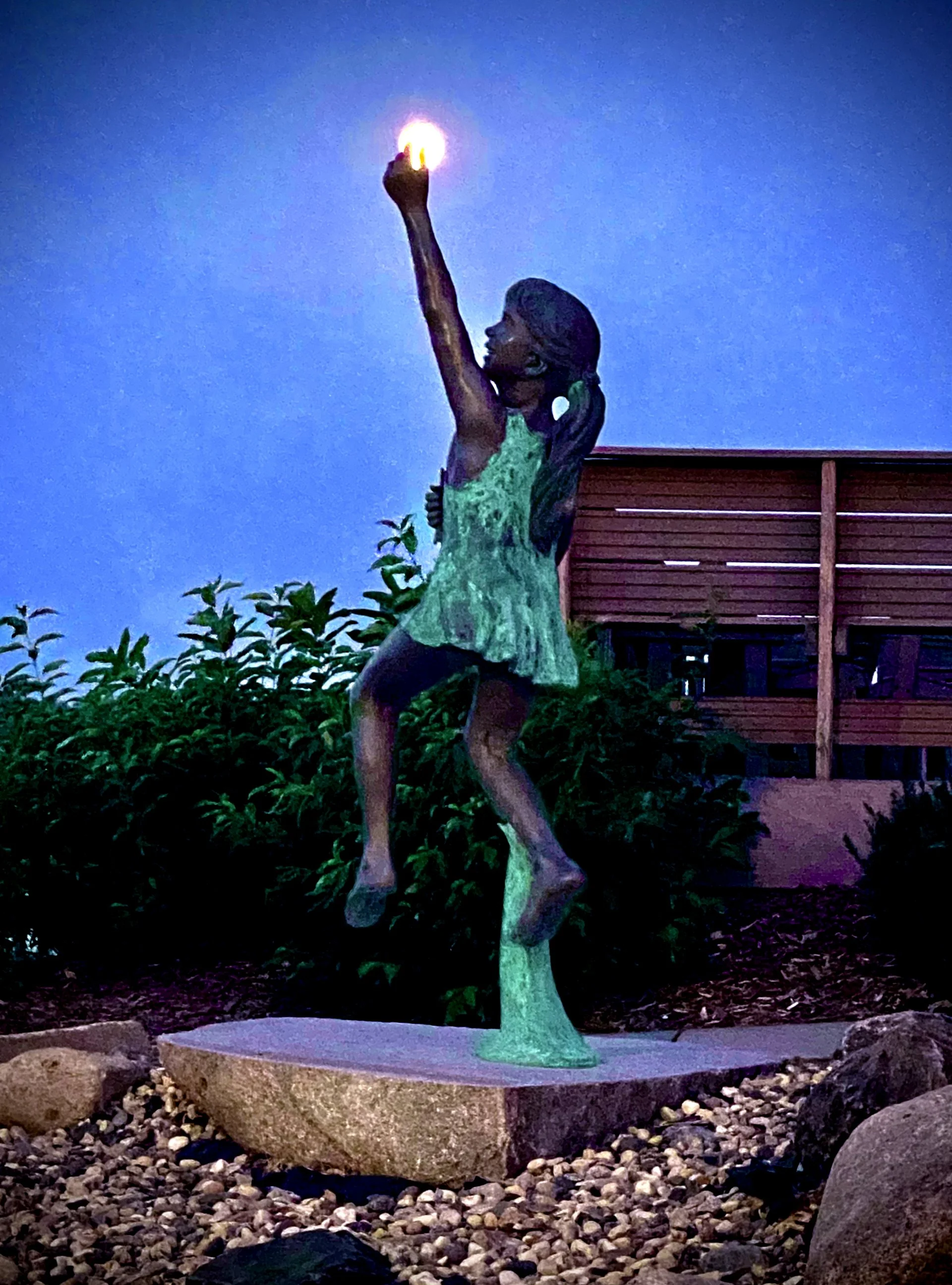 Patinaed statue of the girl at Pirrotta Park; it’s dusk, and she looks like she's holding the moon