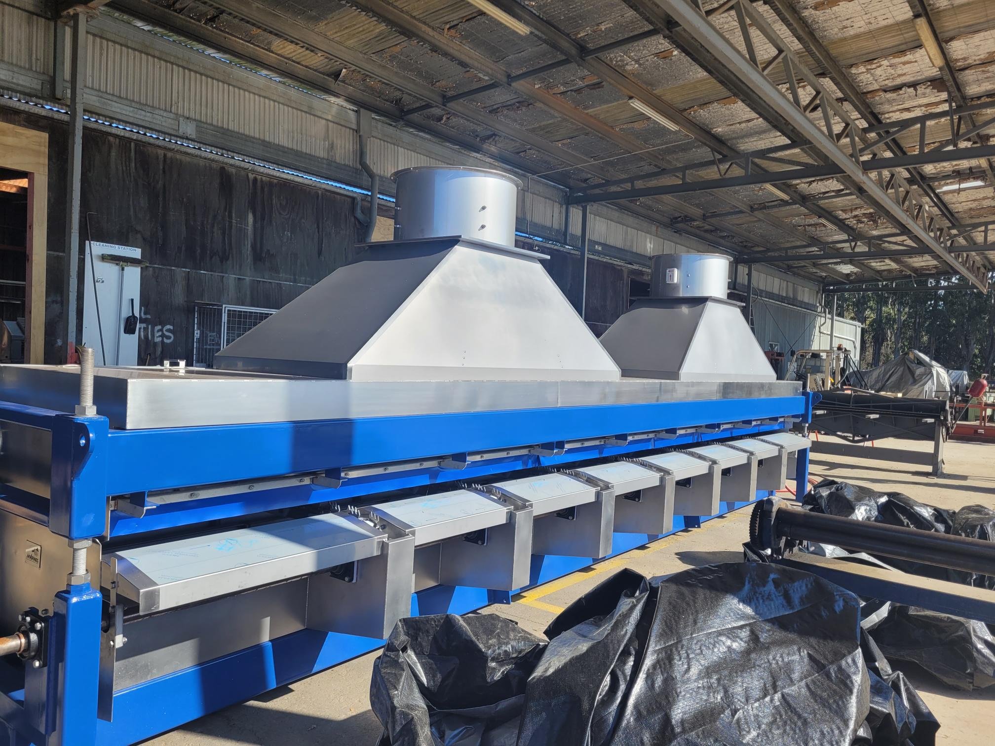 Industrial machinery for manufacturing or processing under a metal roof.
