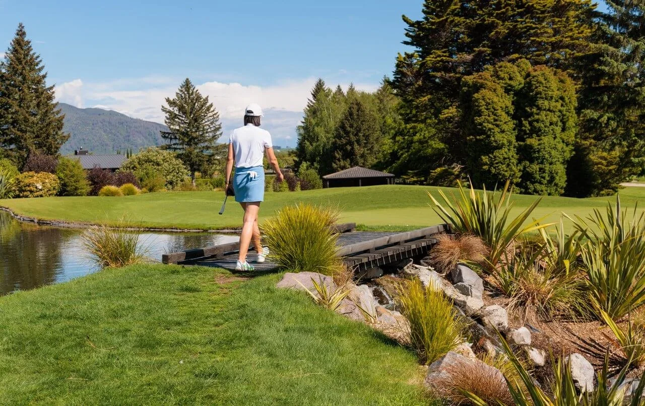 Golfer walking across a wooden bridge at Wairakei Golf and Sanctuary in Taupō New Zealand